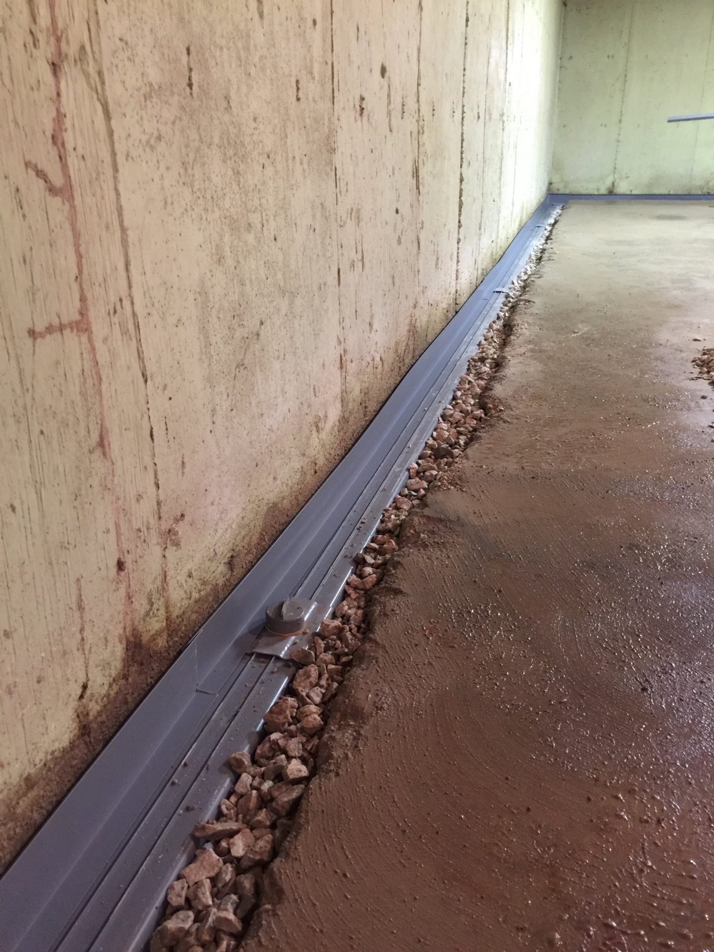 Basement wall drainage system with gravel trench