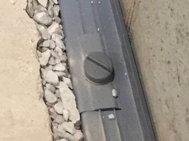 Close-up of gray drainage channel beside gravel