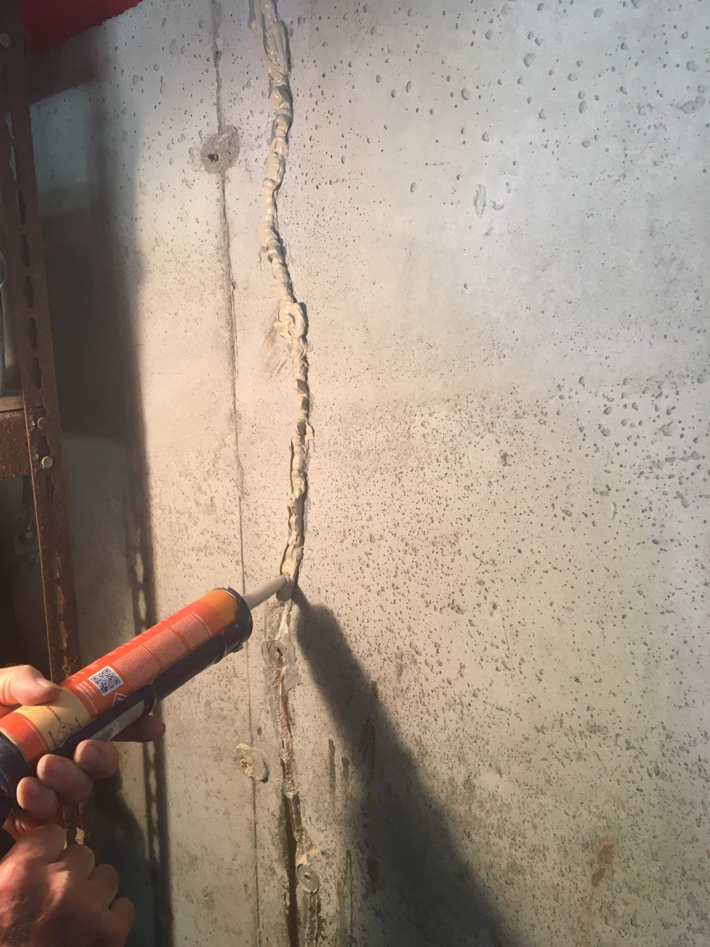 Applying sealant to crack in concrete wall