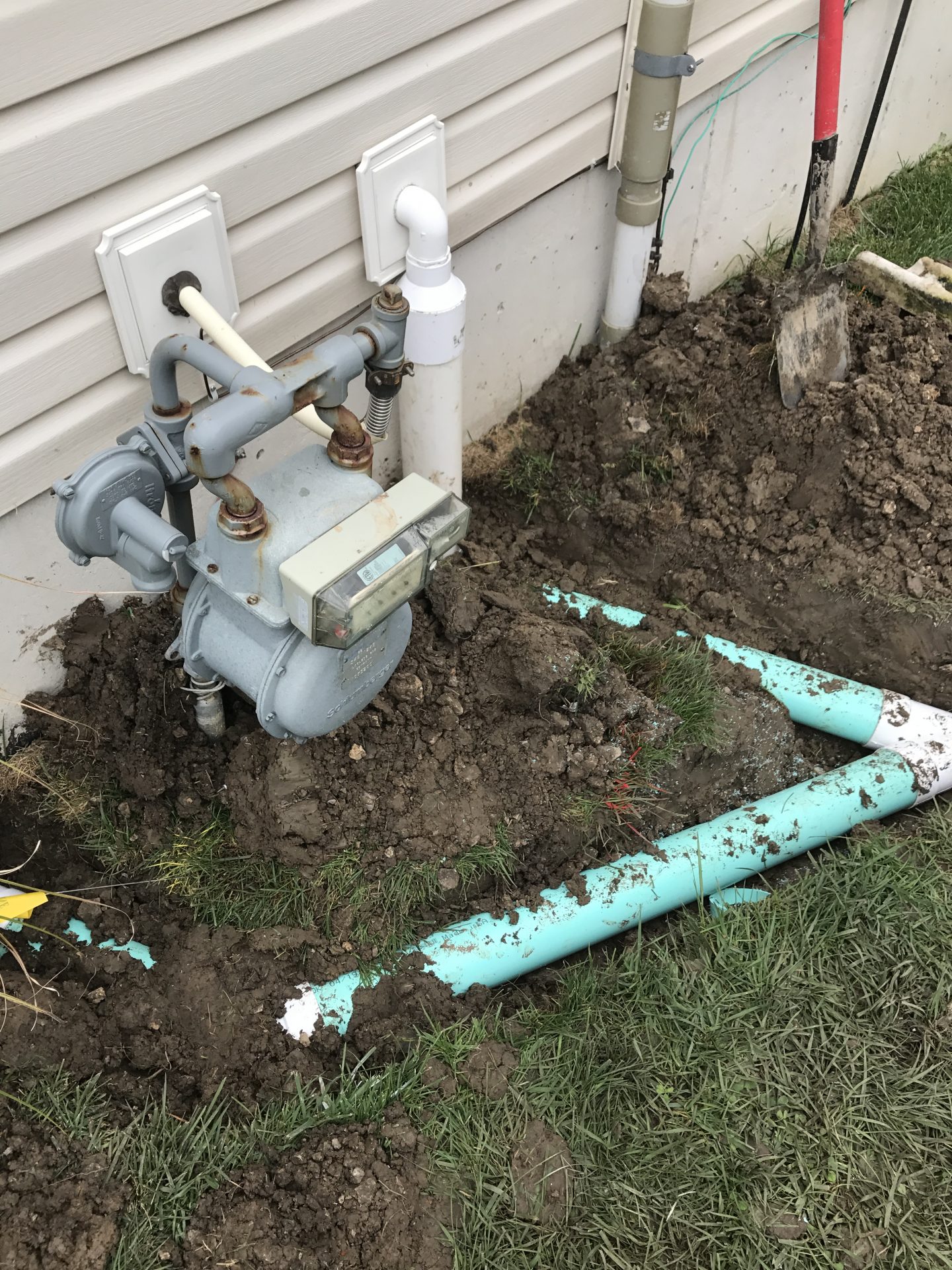 Gas meter and exposed underground pipes beside house