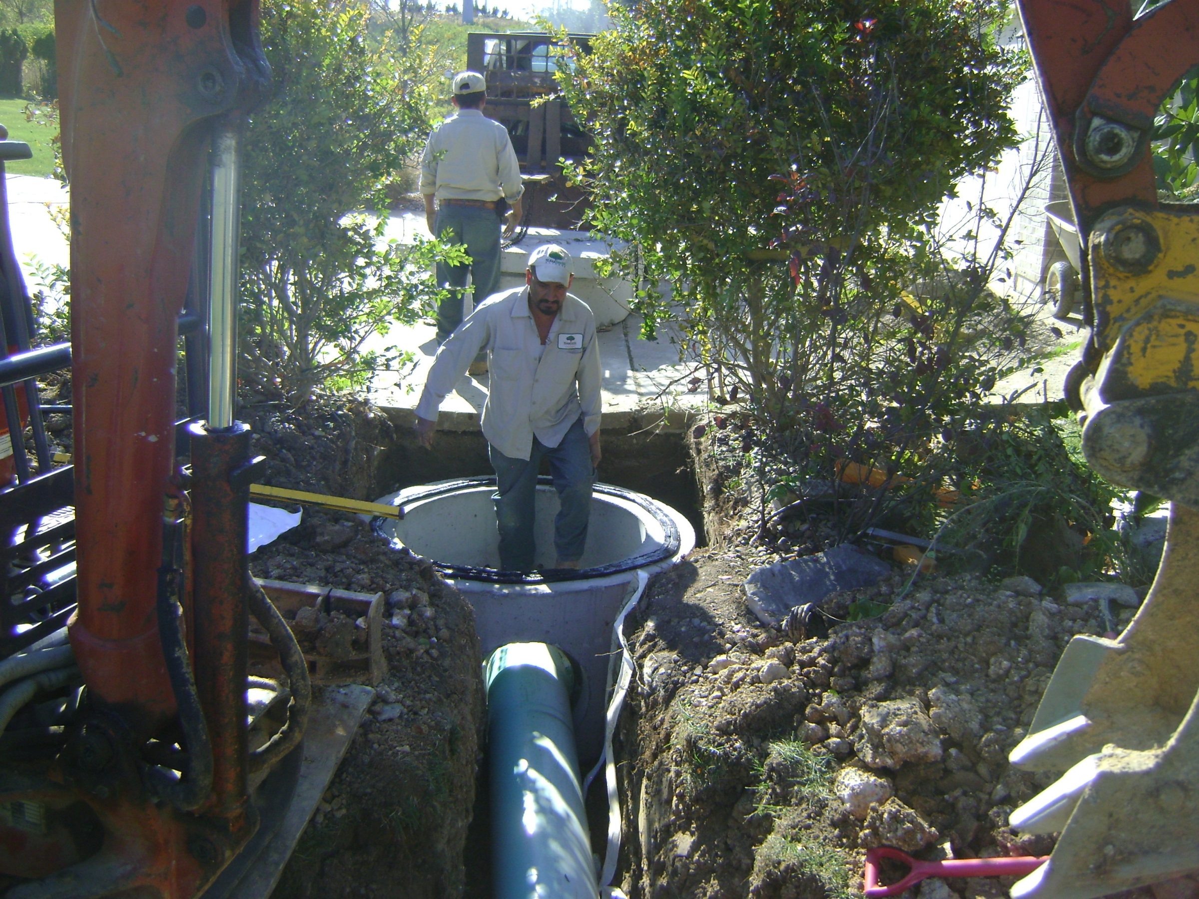 Workers installing underground pipe in excavation site