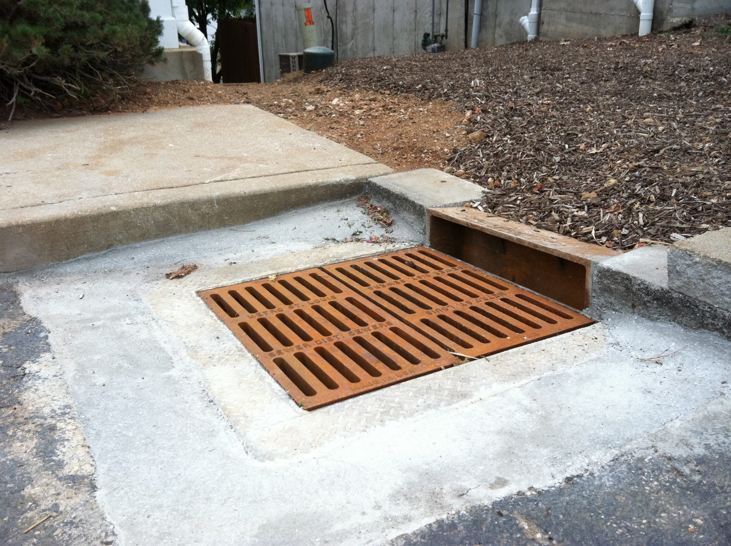 Rusty storm drain grate beside concrete curb