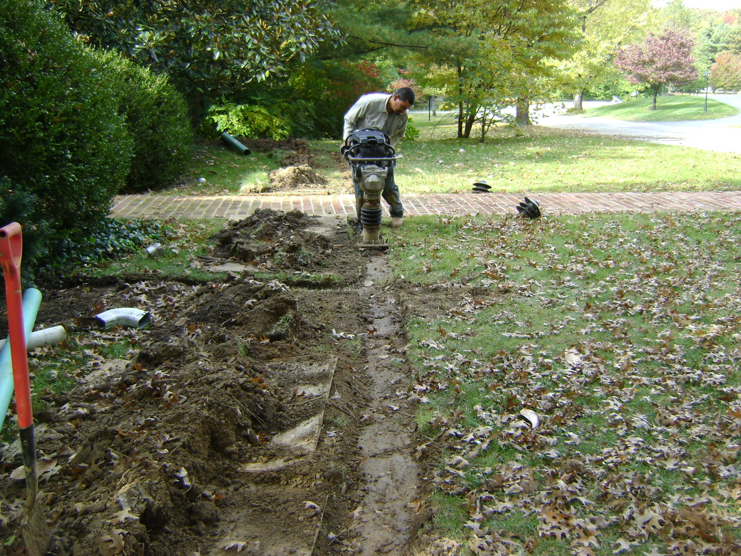 Worker compacting soil in backyard trench