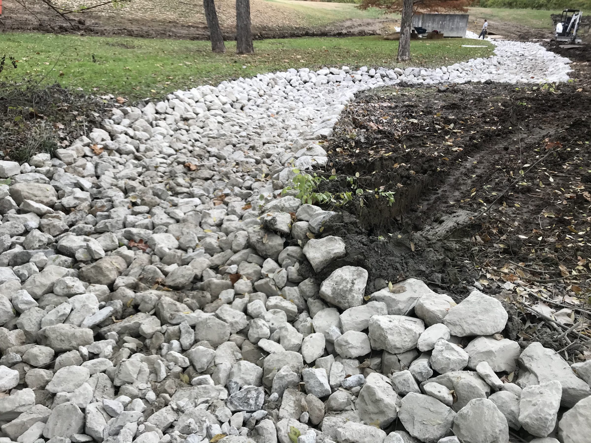 Rock-lined drainage ditch under construction
