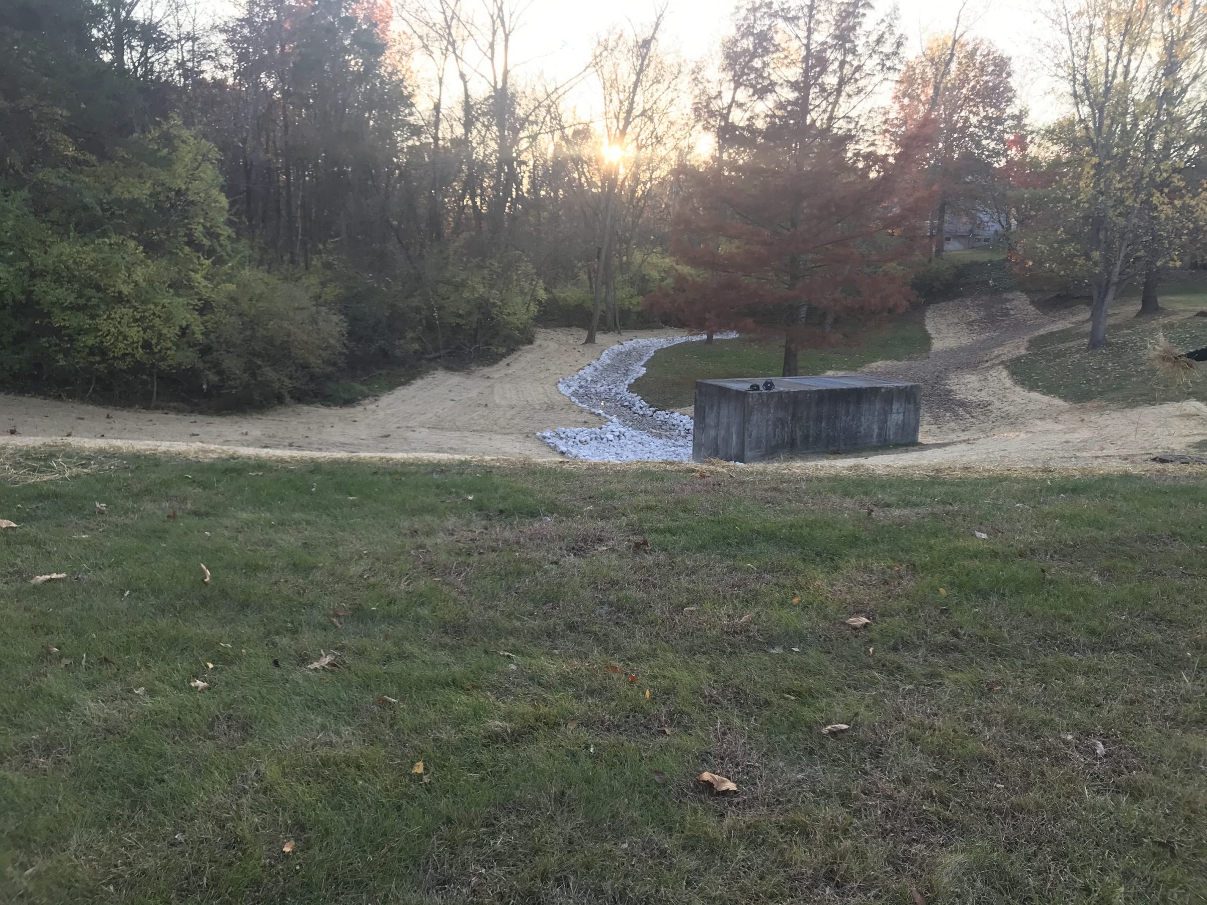 Sunset over park drainage ditch and trees