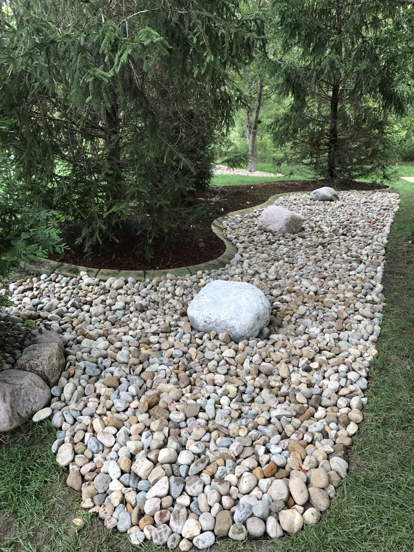 Landscaped garden bed with river rocks and boulders