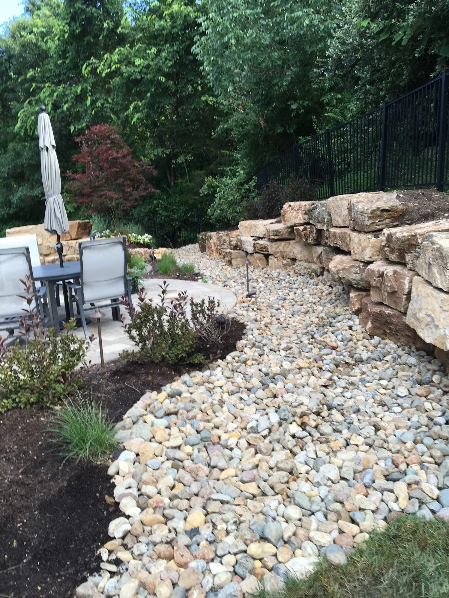 Backyard patio with stone wall and river rocks