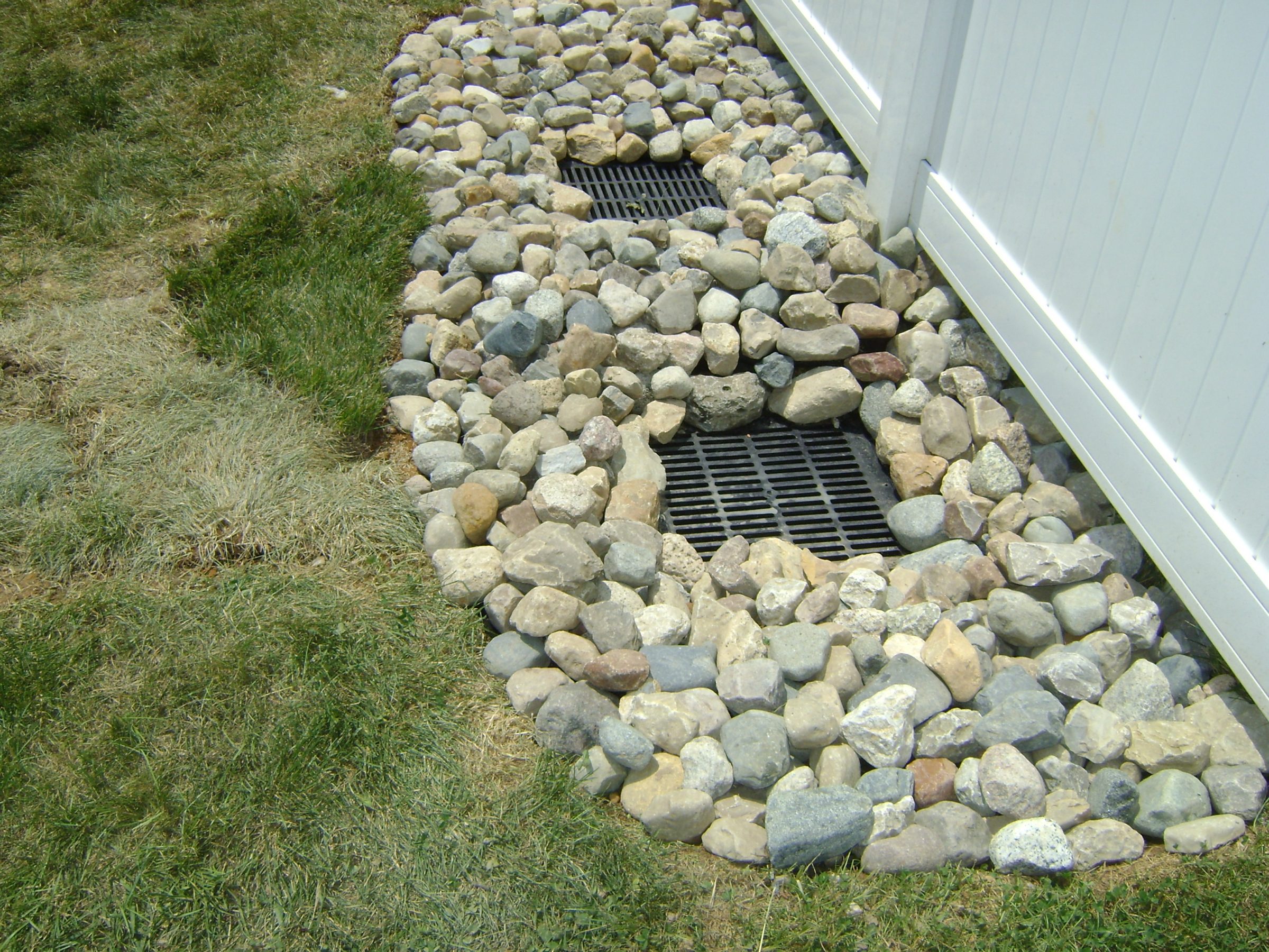 Rock-lined drainage trench with metal grates