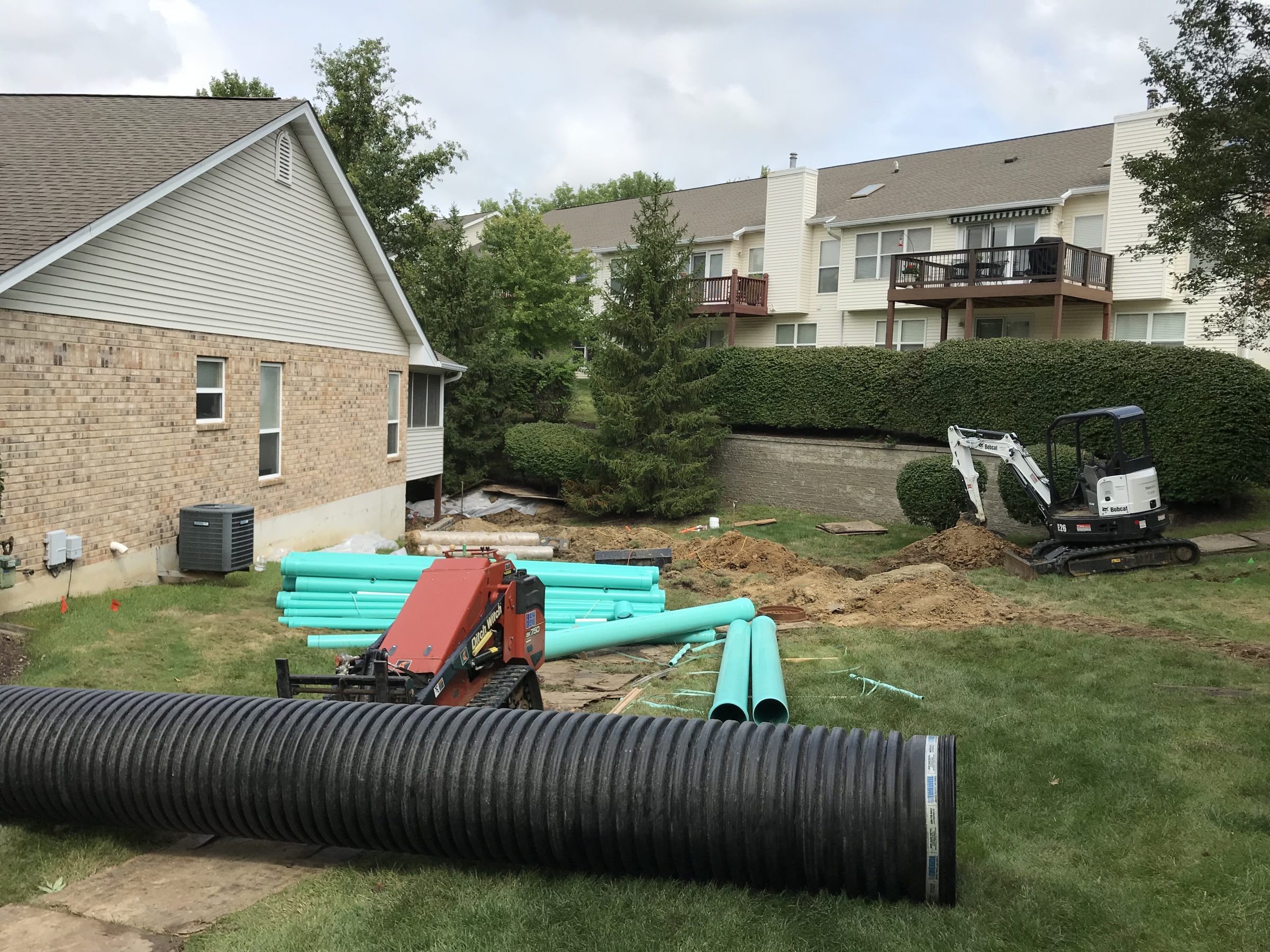 Residential backyard construction with excavator and drainage pipes