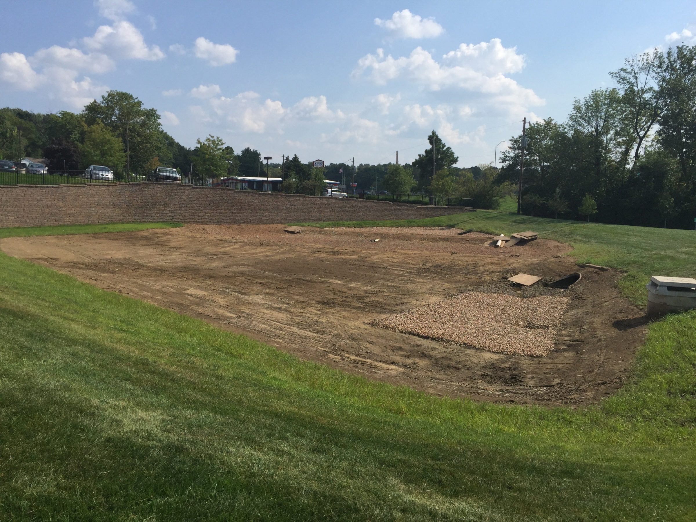 Excavated dirt basin under construction near retaining wall