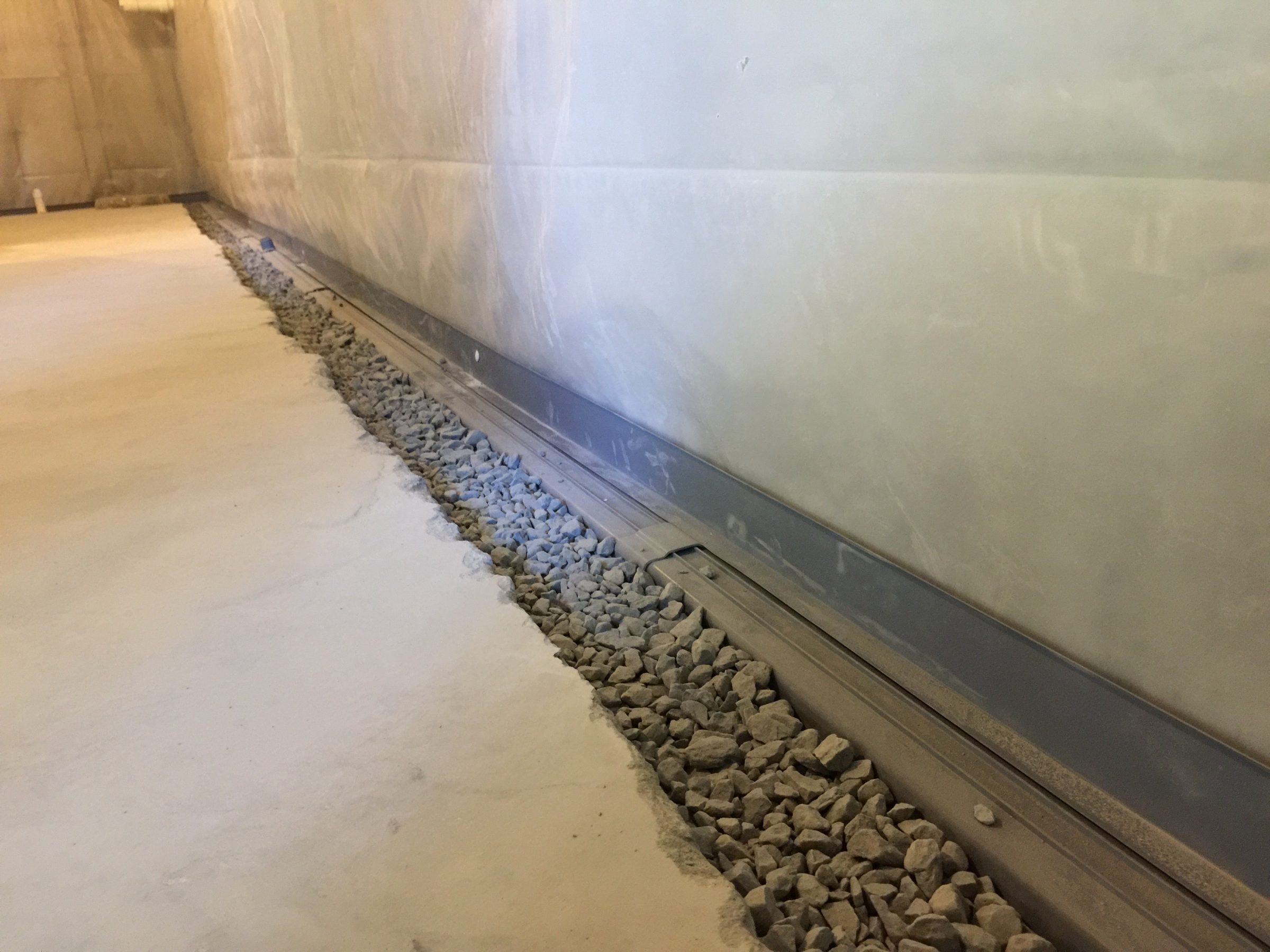 Basement wall drainage system with gravel trench
