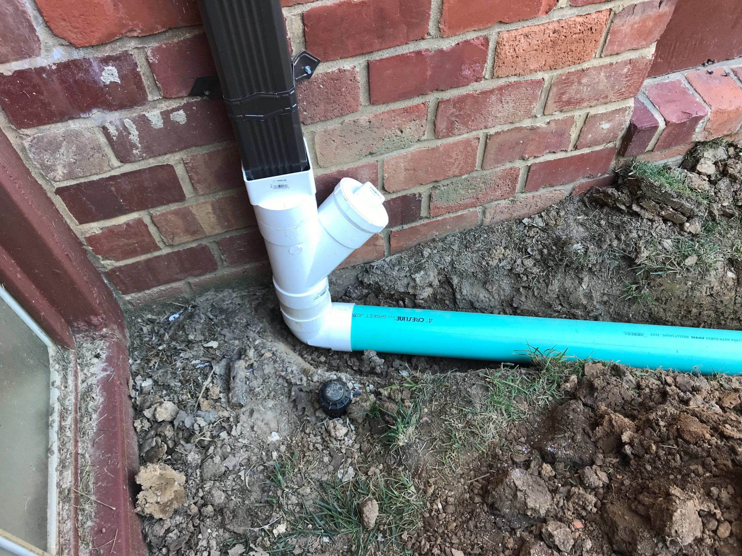 Downspout connected to underground PVC drainage pipe