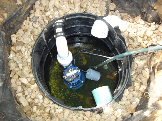 Sump pump inside basin with water and pipes
