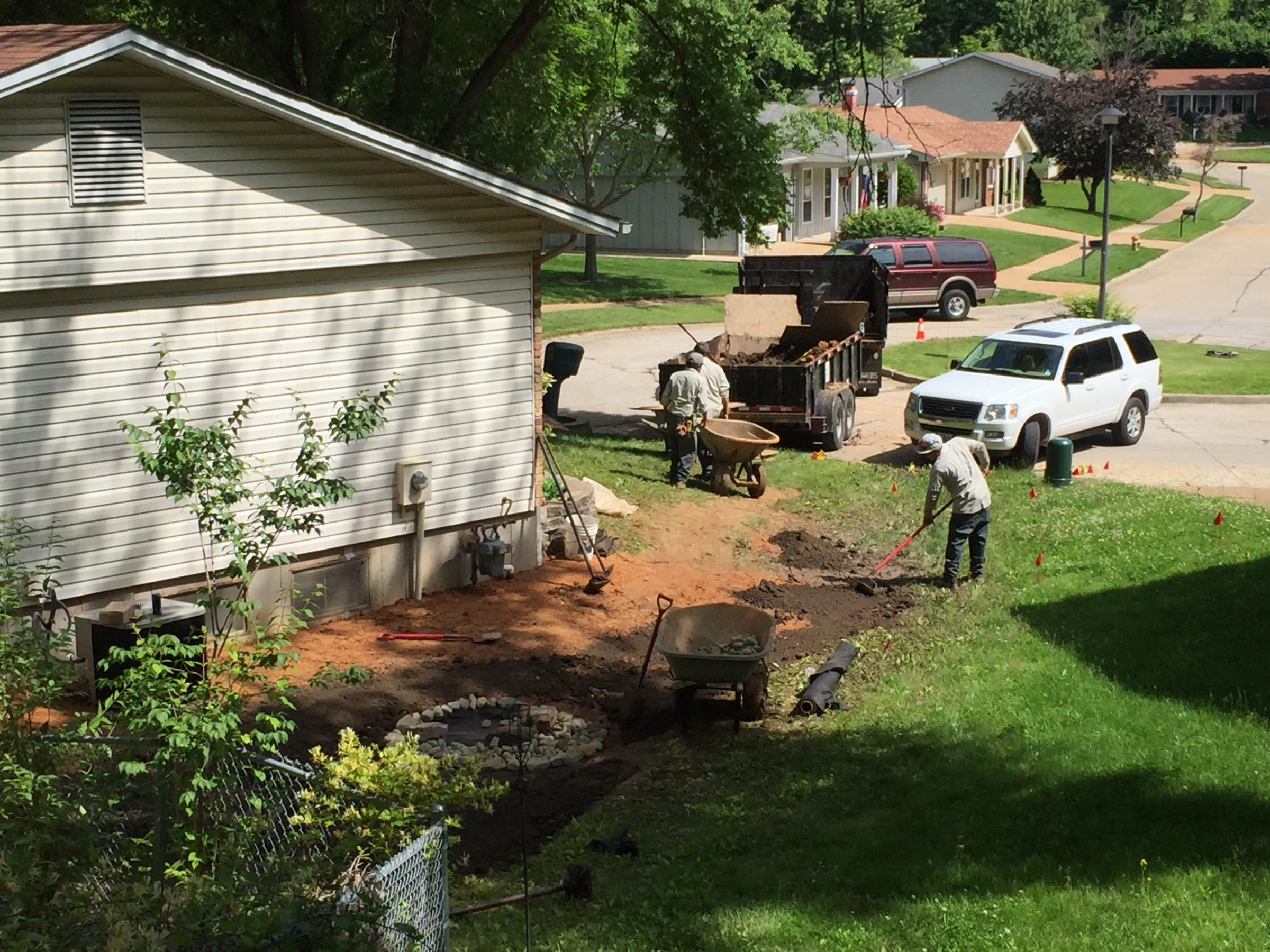 Workers landscaping yard beside suburban home