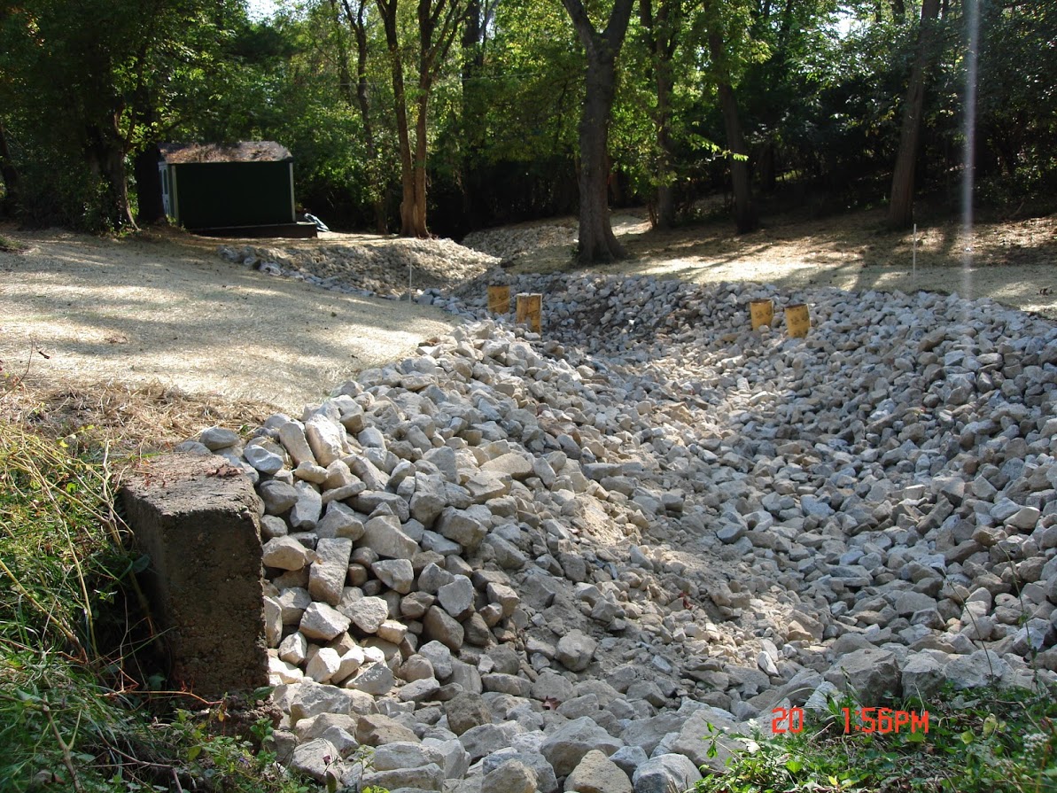 Rock-lined drainage ditch in wooded area