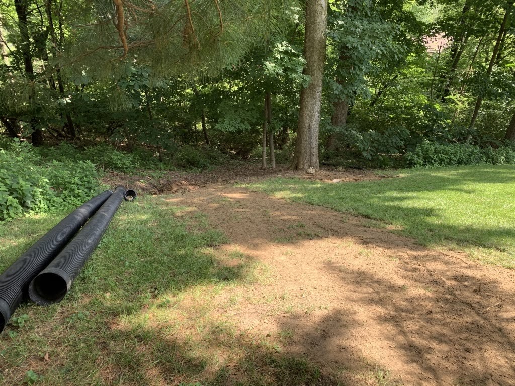 Drainage pipes beside grassy yard near wooded area