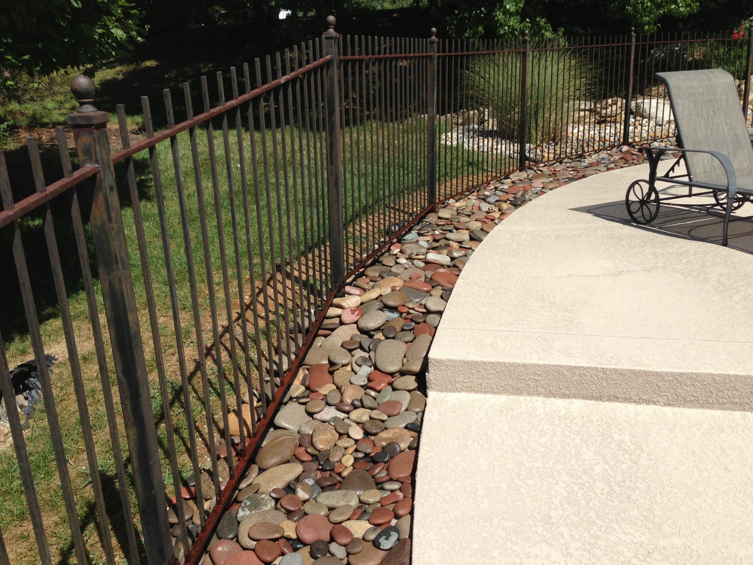 Curved patio with metal fence and river rocks
