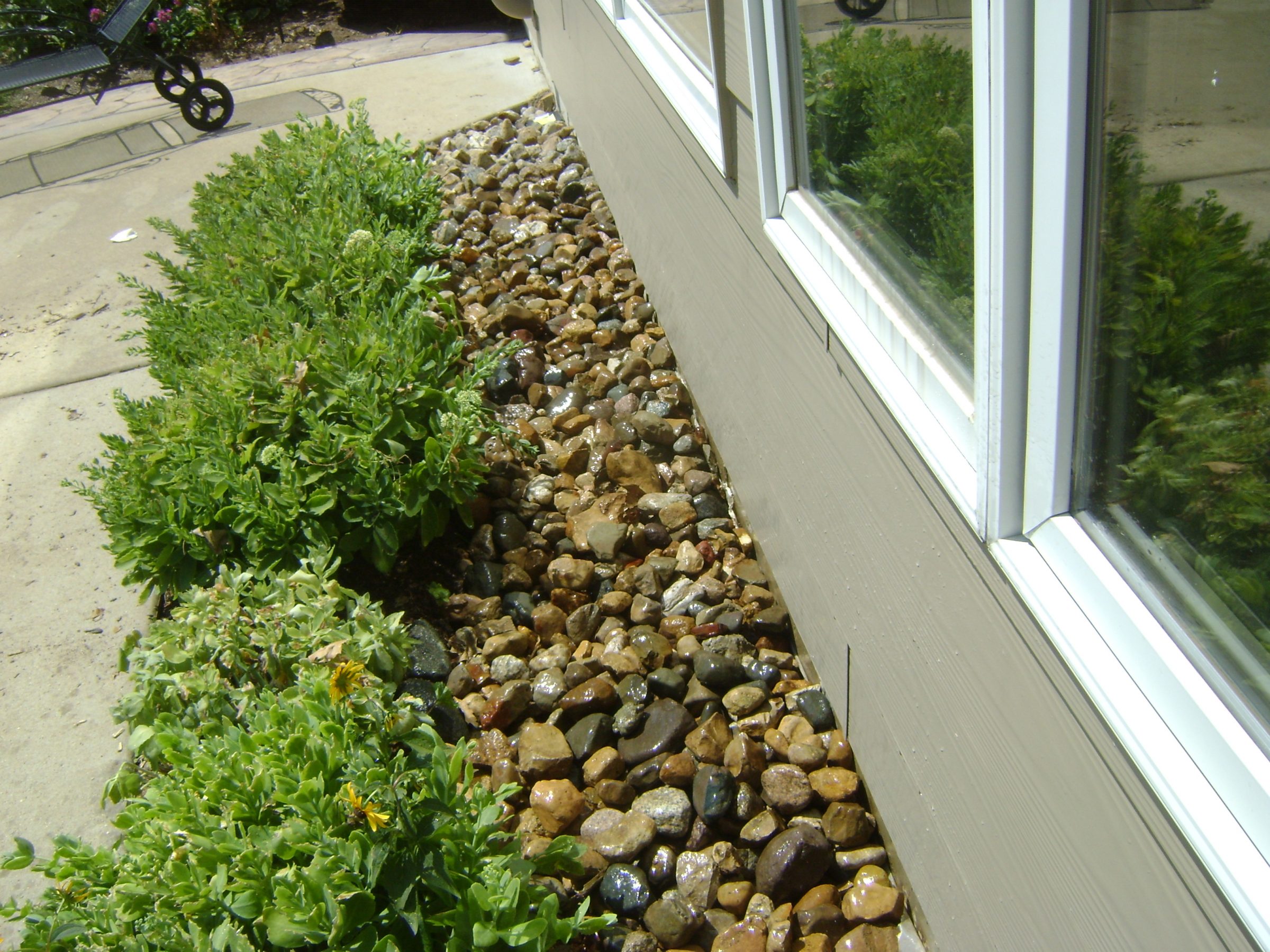 River rock landscaping beside house window and garden