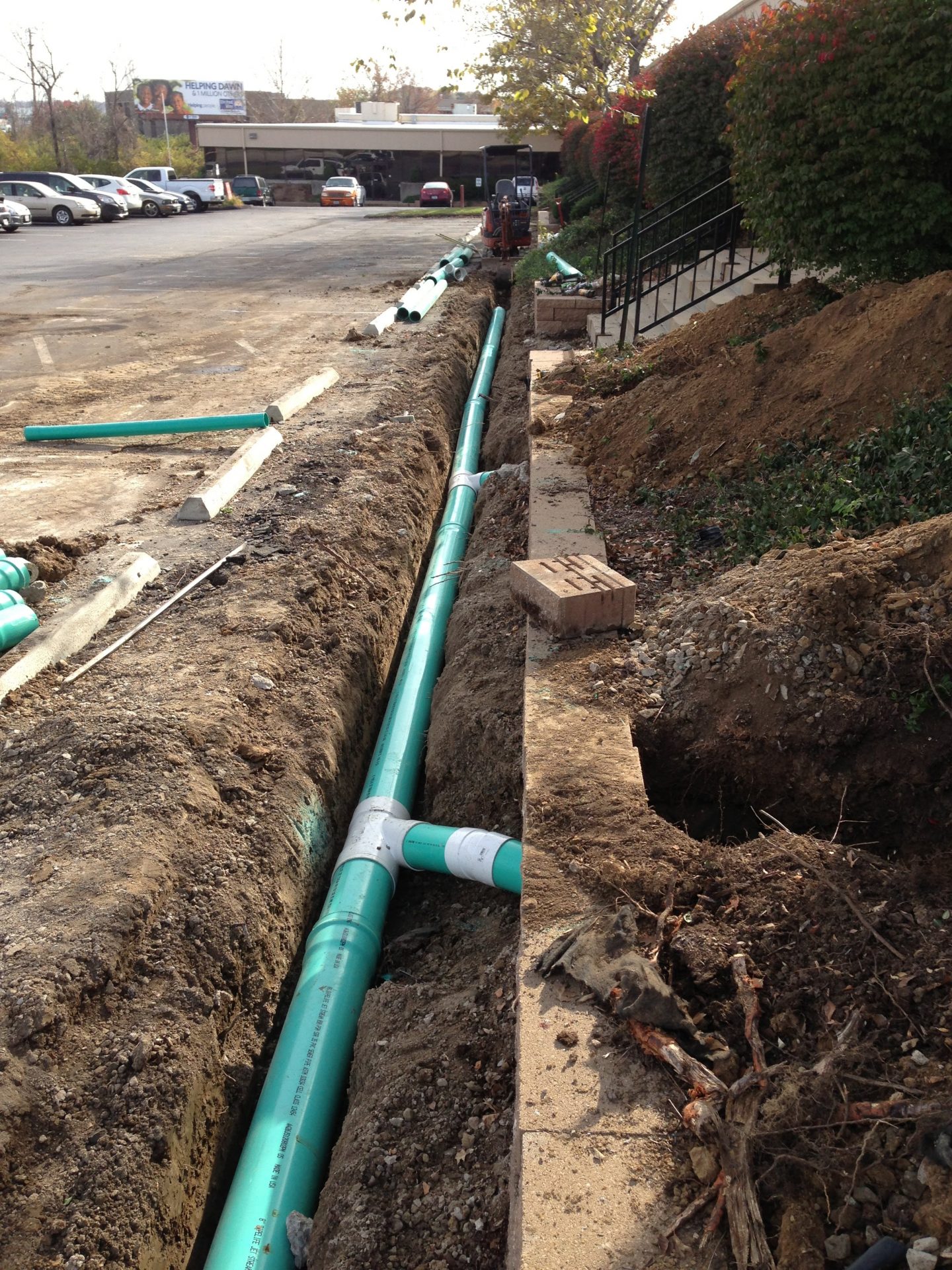 Green PVC pipes installed in parking lot trench