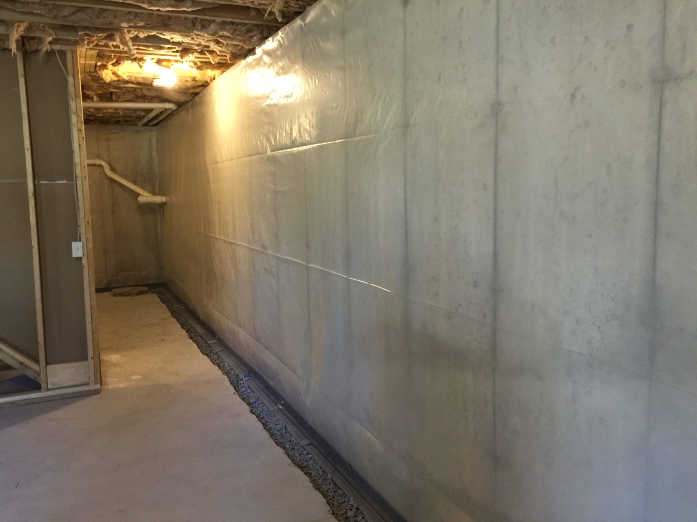 Basement wall with vapor barrier and drainage system