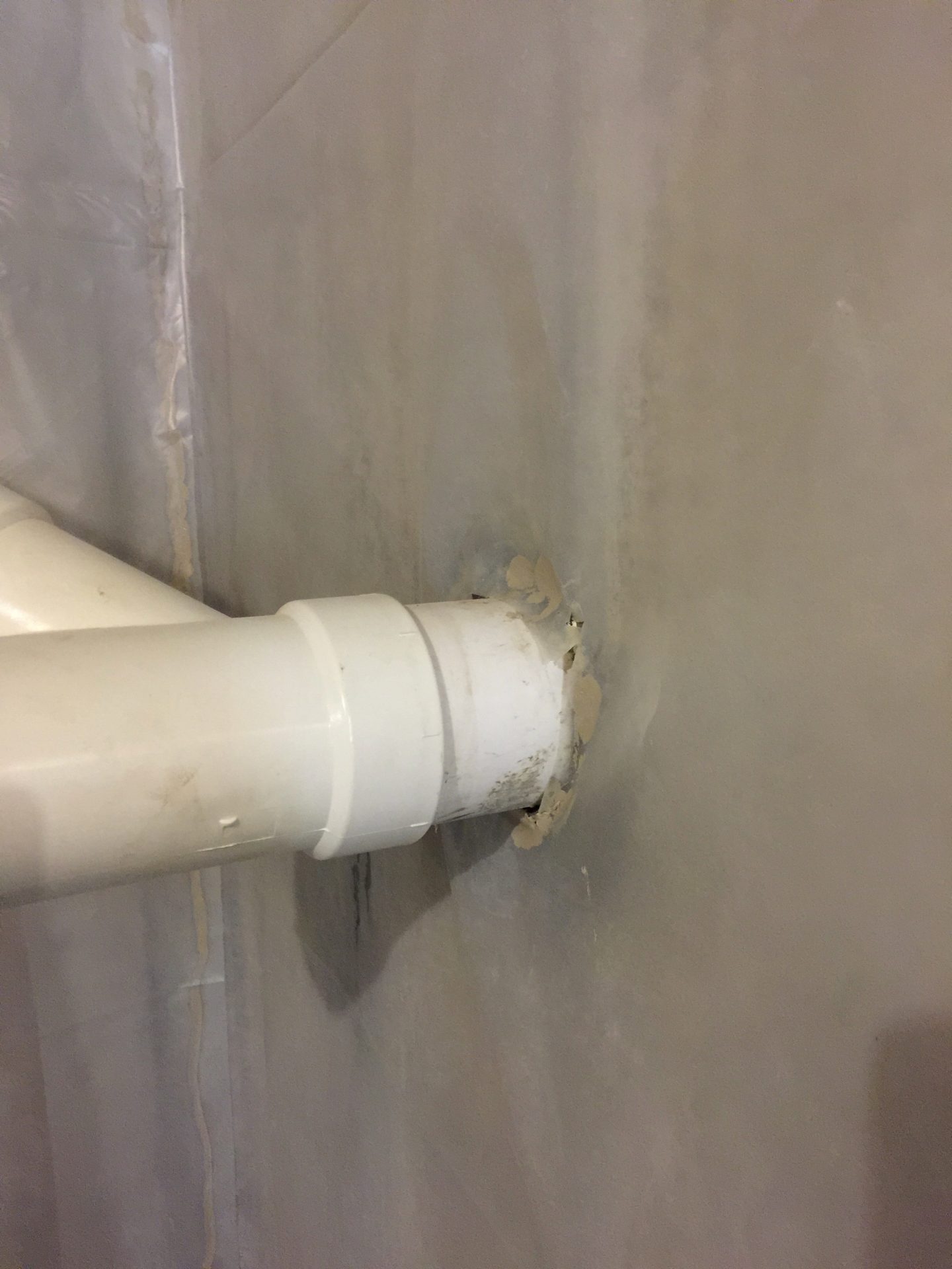 White PVC pipe entering wall with sealant