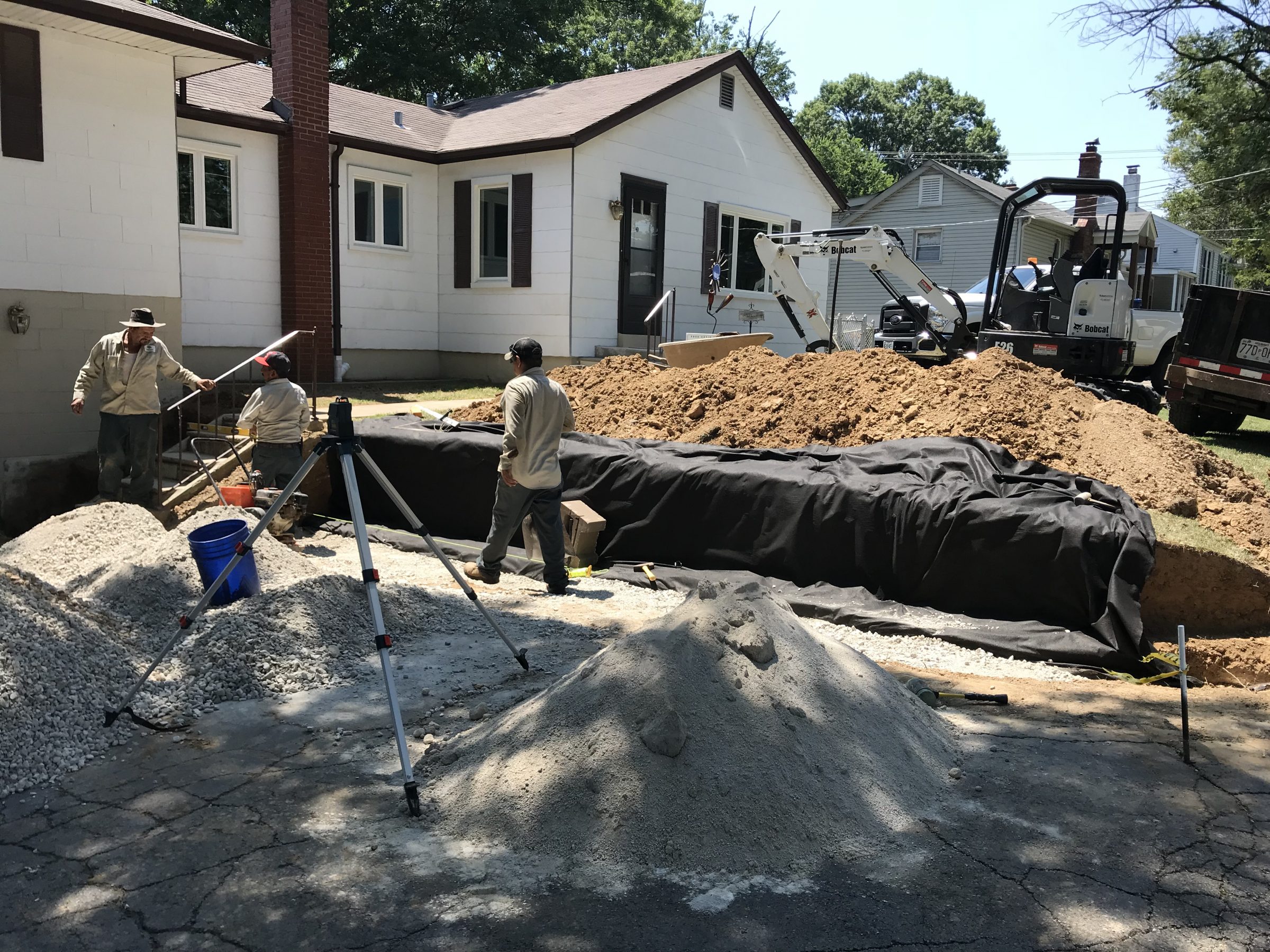 Workers excavating foundation beside suburban home