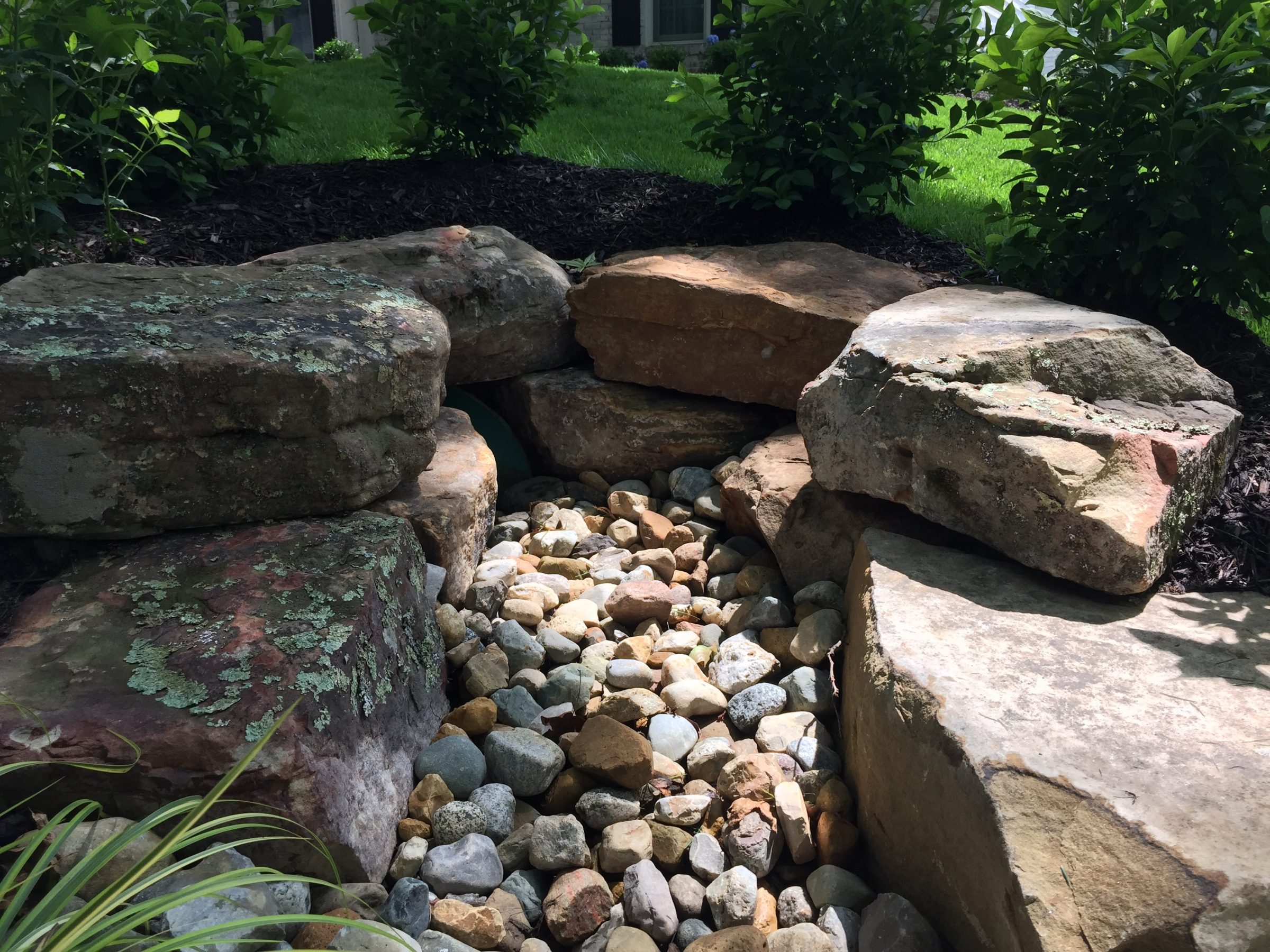 Stacked stone garden feature with pebbled dry creek
