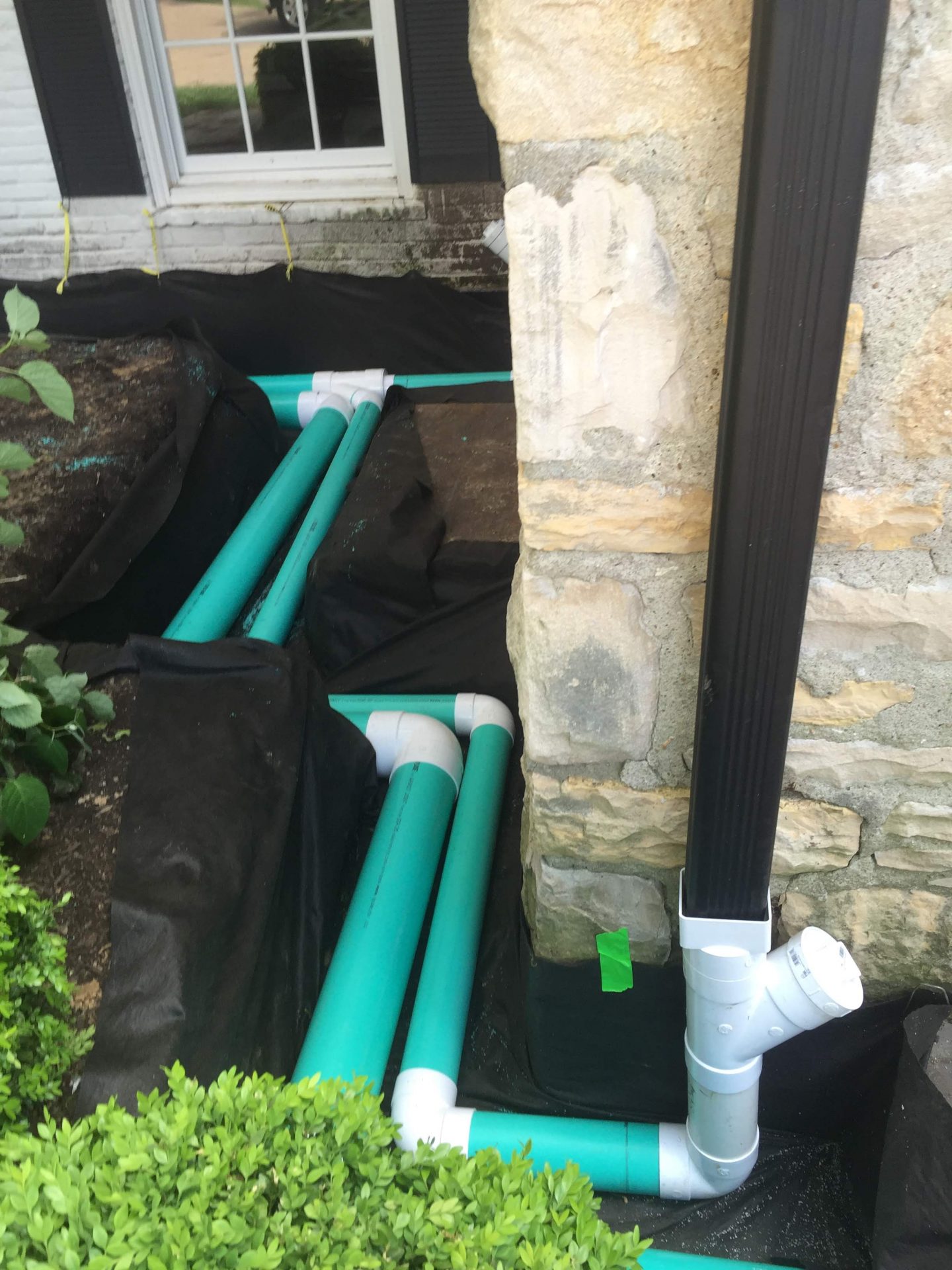 Exterior foundation drainage pipes beside house wall
