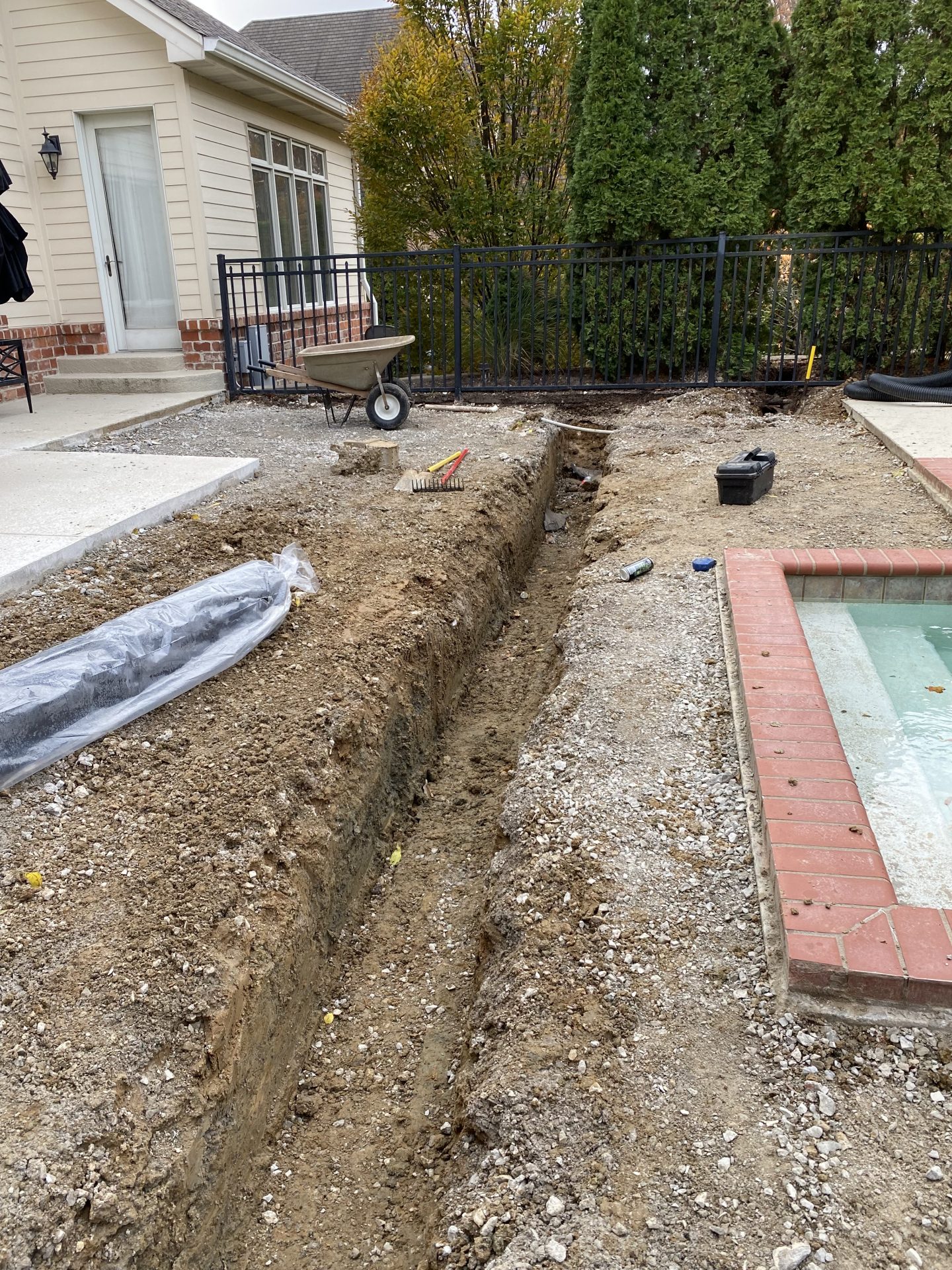 Backyard trenching project beside pool and house