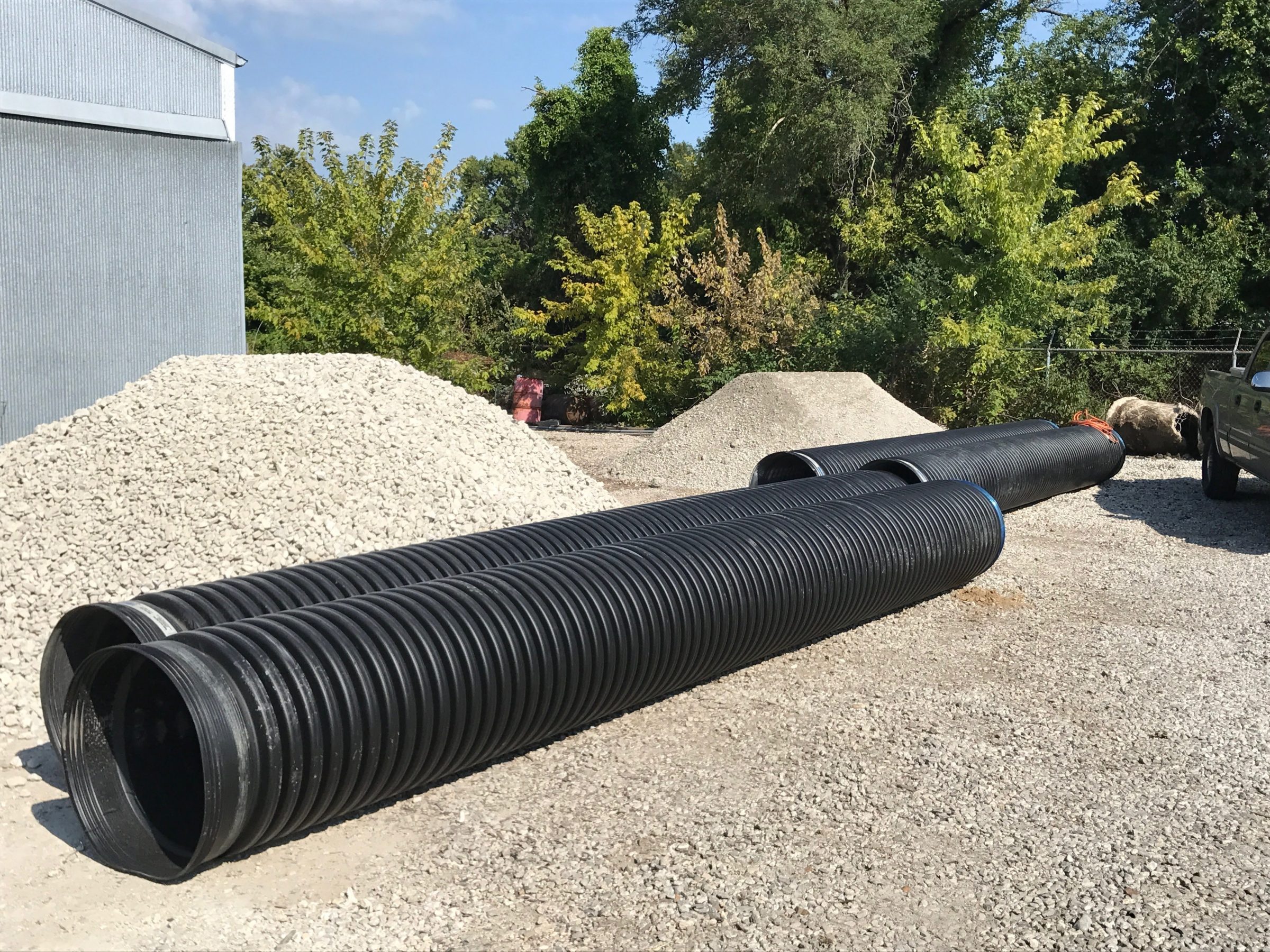 Large black corrugated drainage pipes on gravel lot