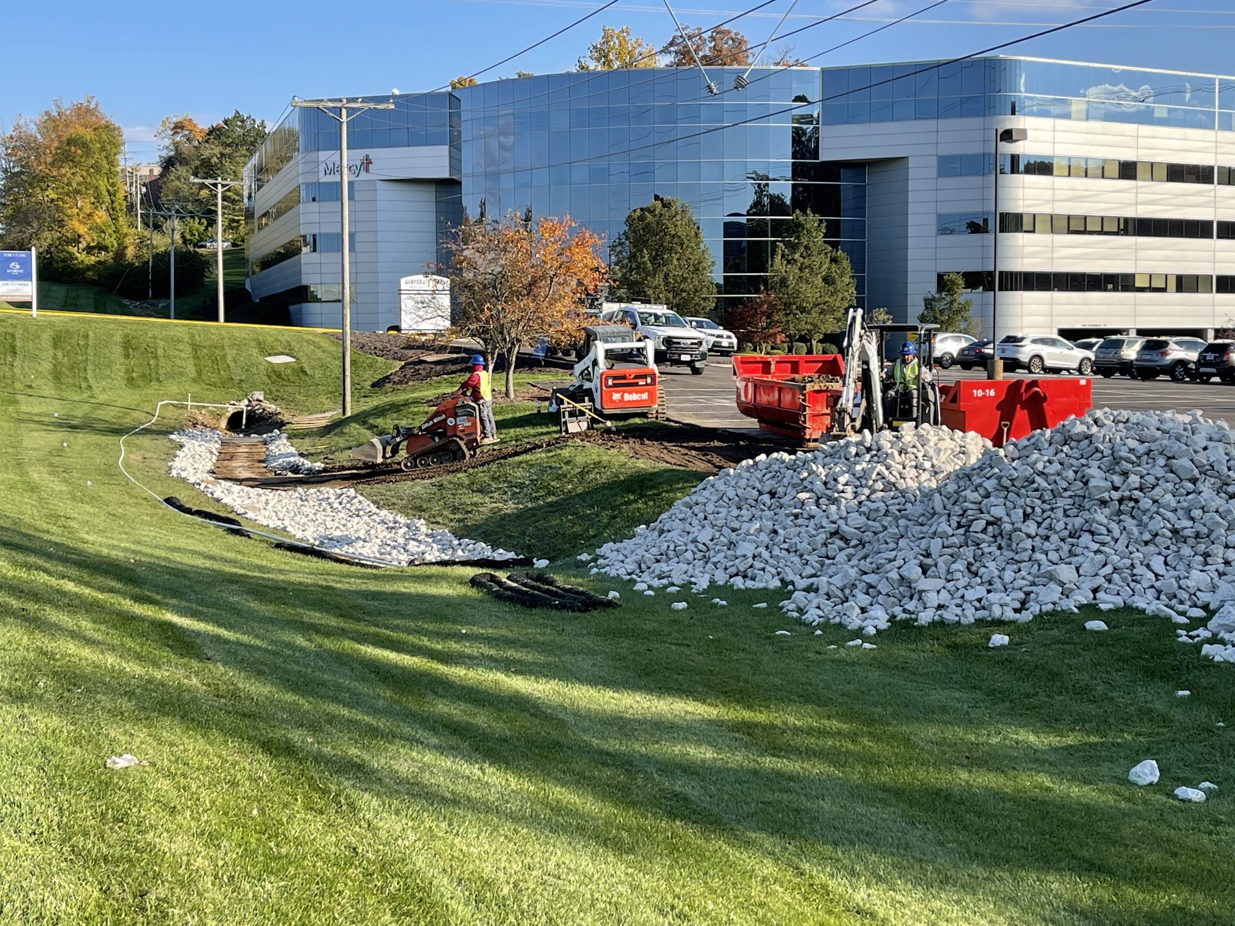 Construction workers installing drainage rocks near office building