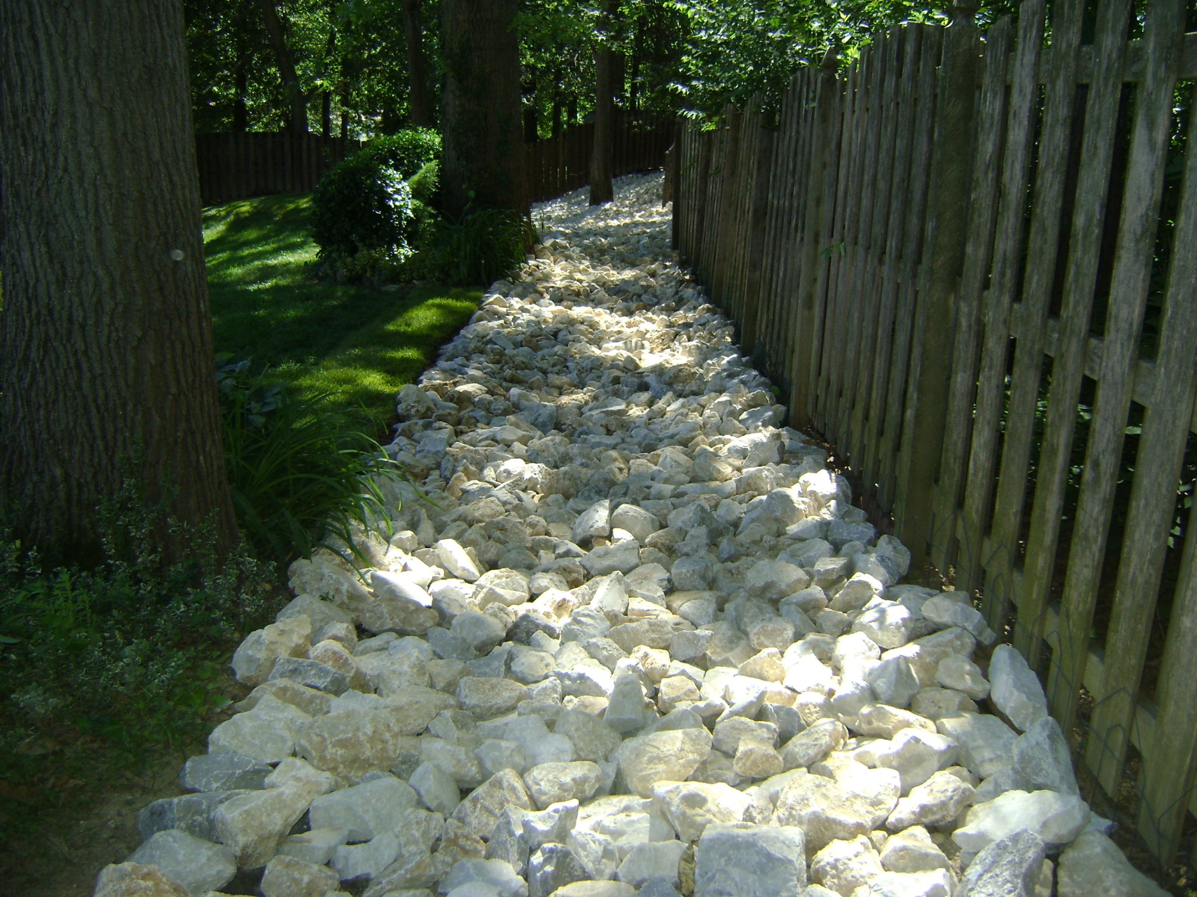 Rock-filled drainage ditch beside wooden fence