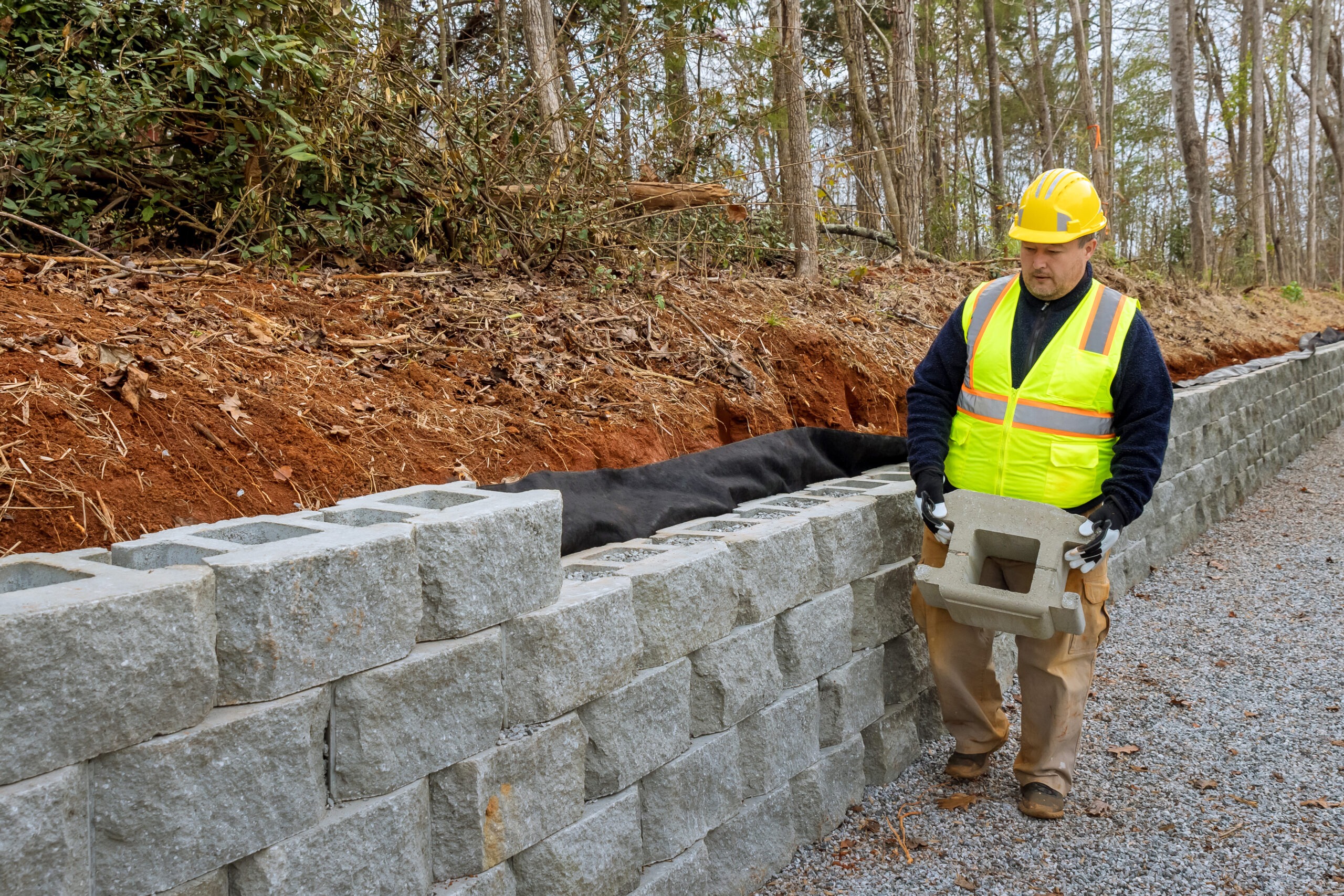 Construction worker building concrete block retaining wall