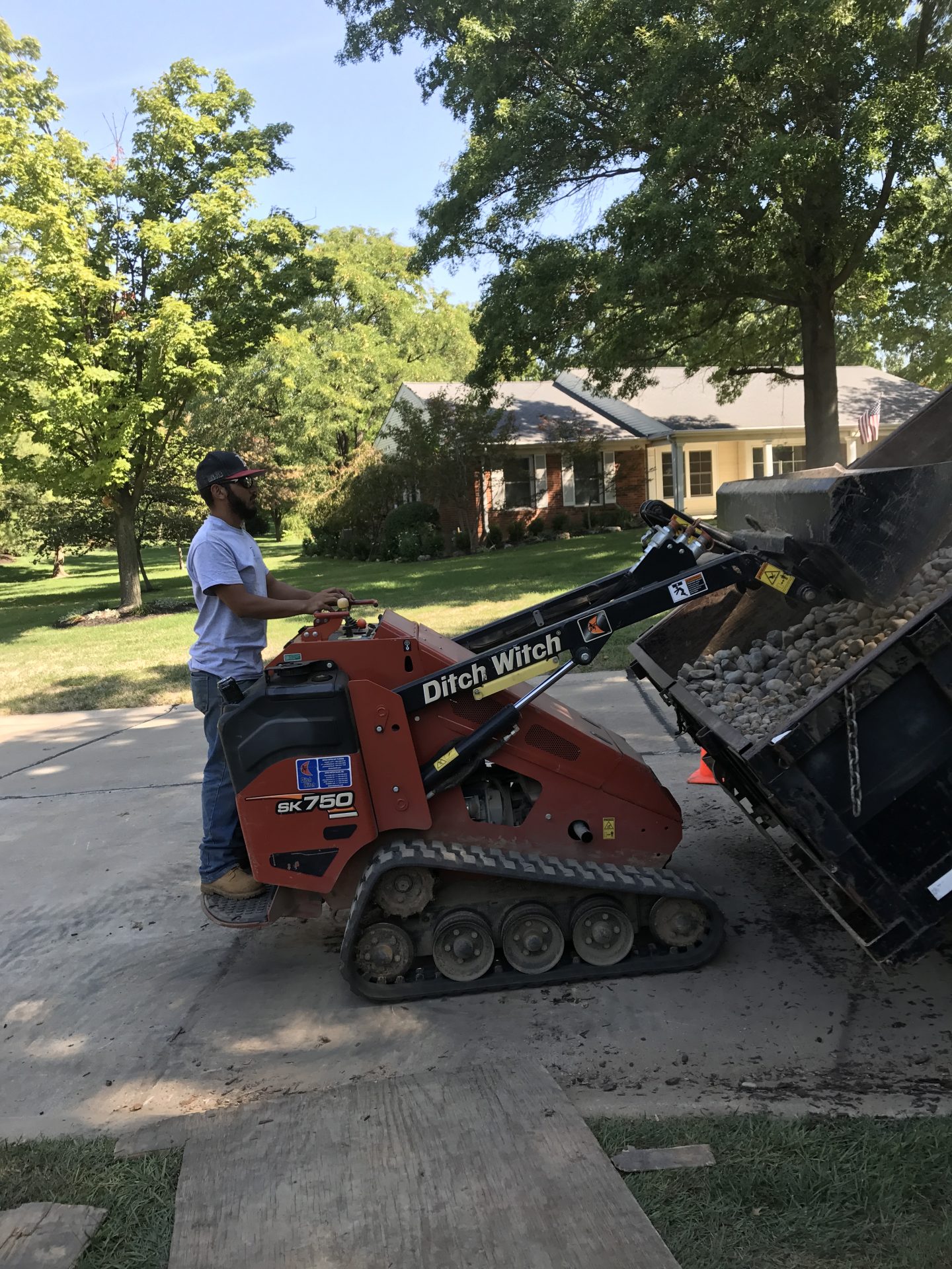 Worker dumping gravel with Ditch Witch loader