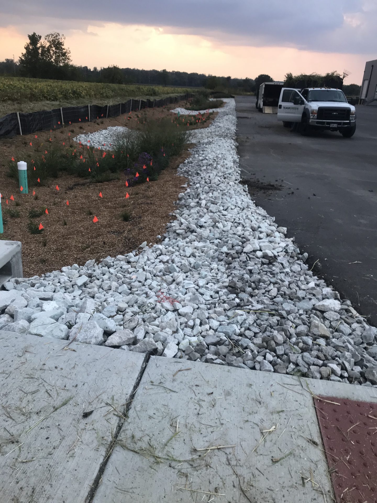 Rock-lined drainage swale beside parking lot at dusk