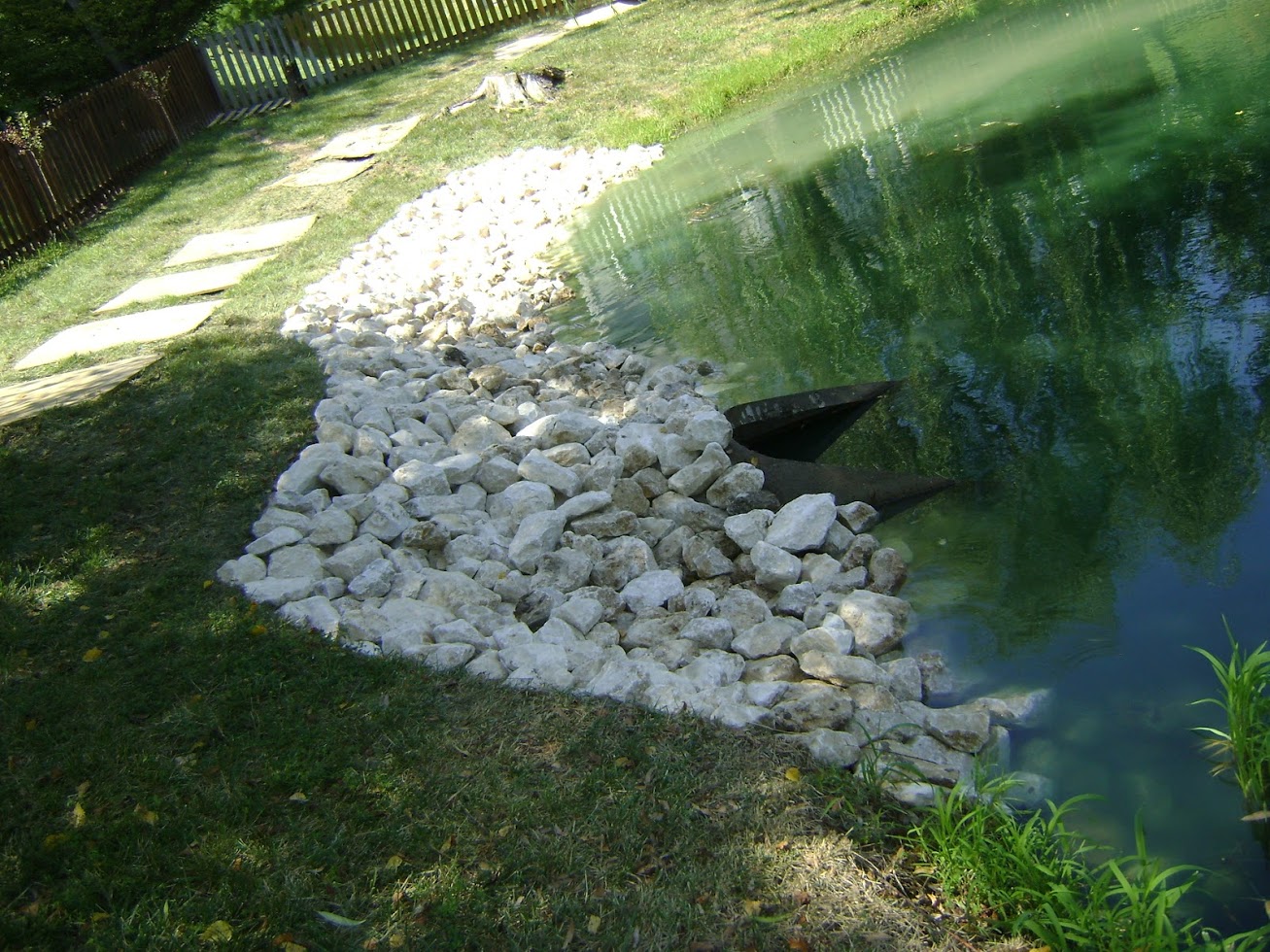 Rock-lined pond edge with drainage pipe