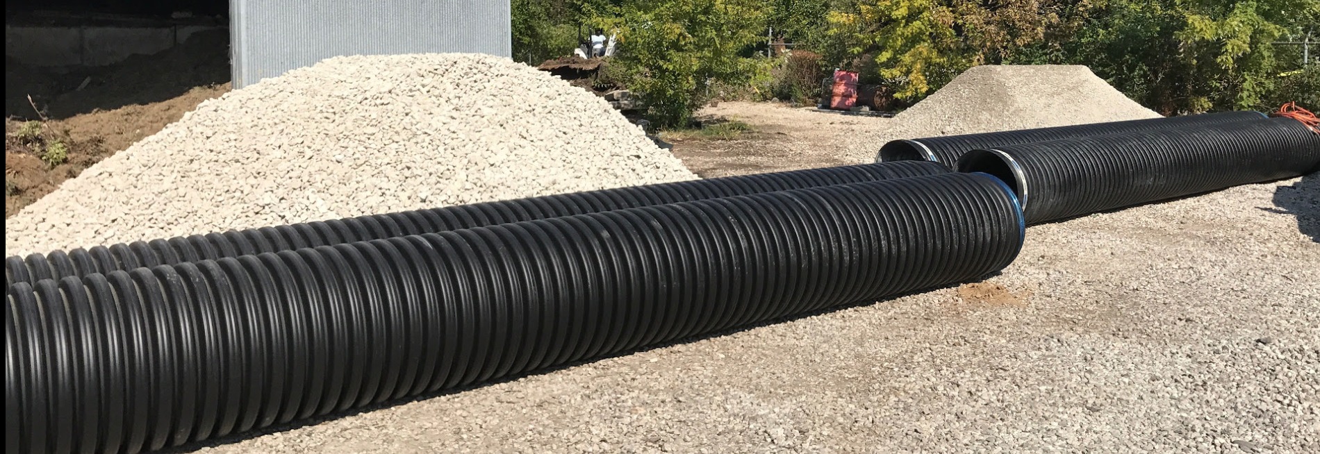 Large black corrugated drainage pipes on gravel