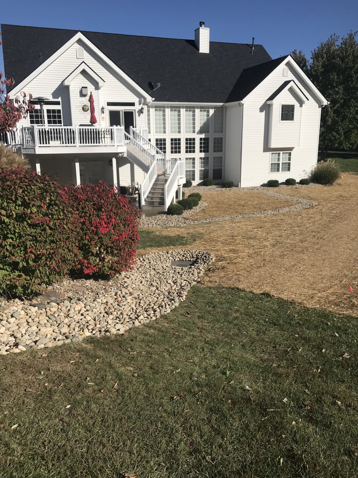 White suburban house with deck and landscaped yard