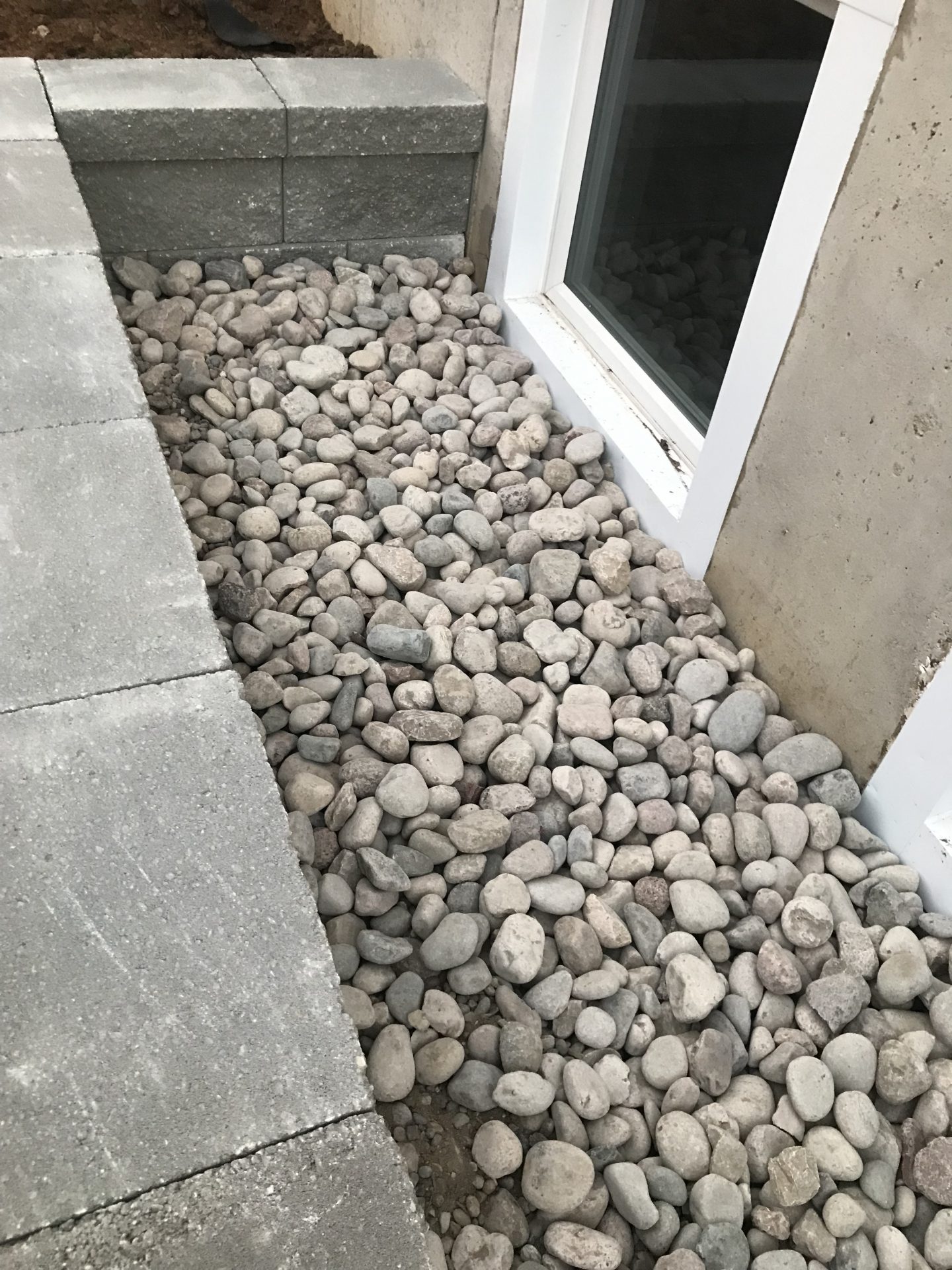 Window well filled with decorative river rocks
