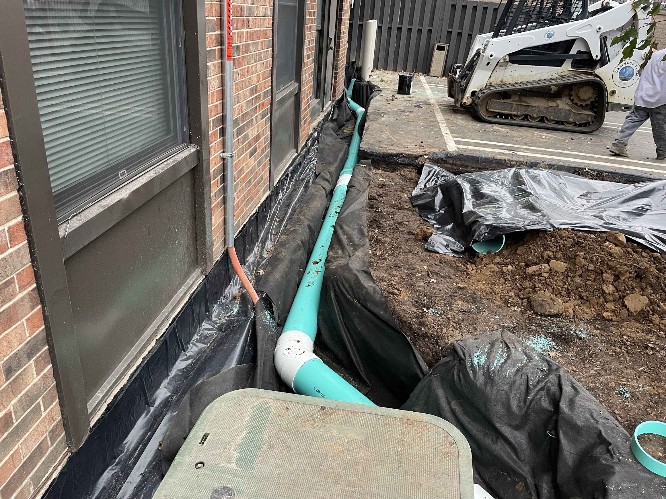 Drainage pipe installation beside brick building foundation