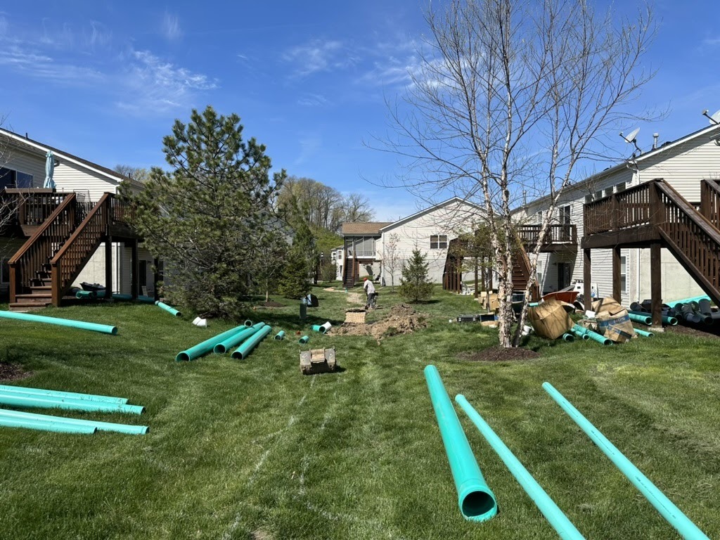 Workers installing green pipes in townhouse yard