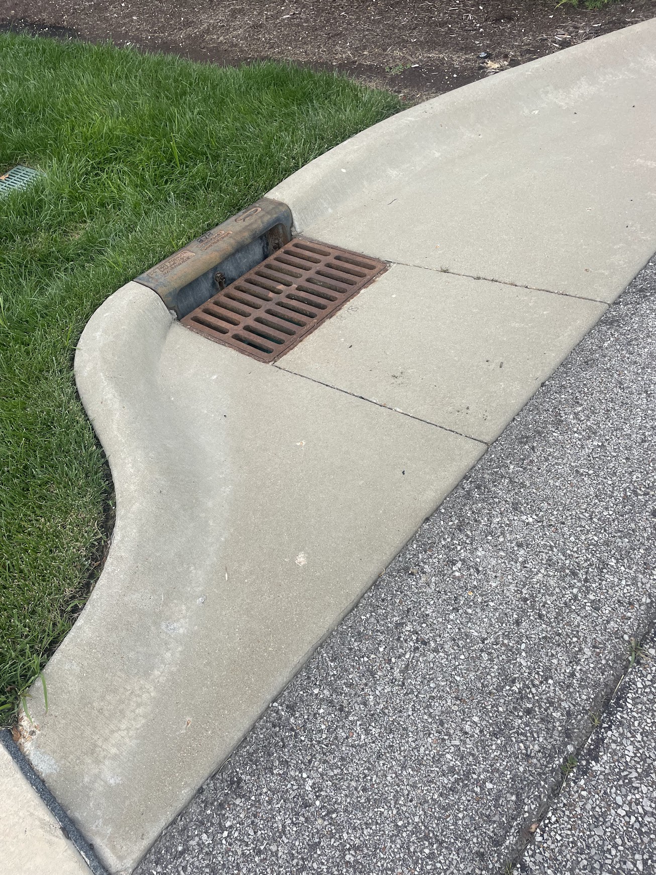 Storm drain grate along concrete curb and street