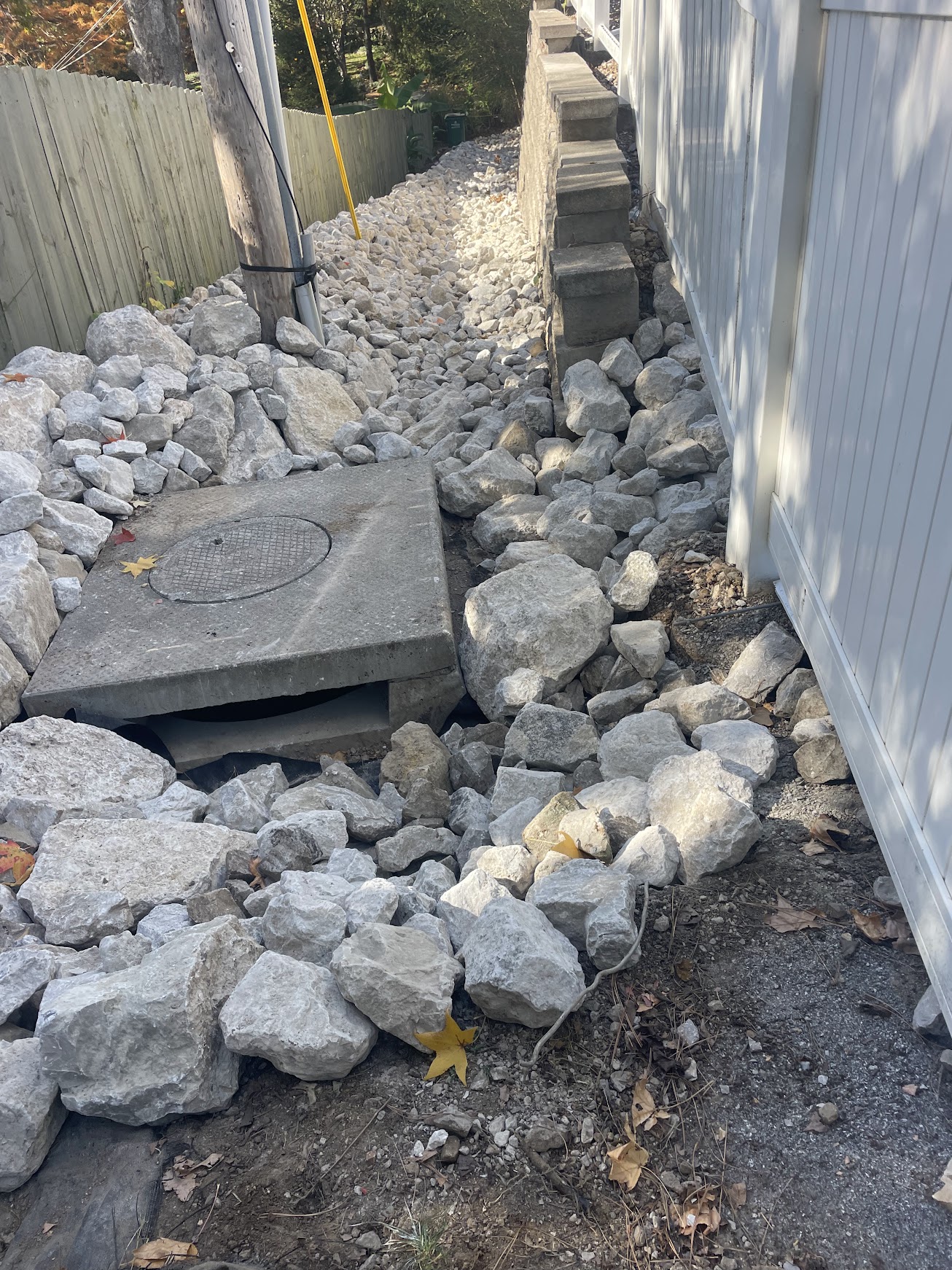 Rock-filled drainage ditch beside house and fence