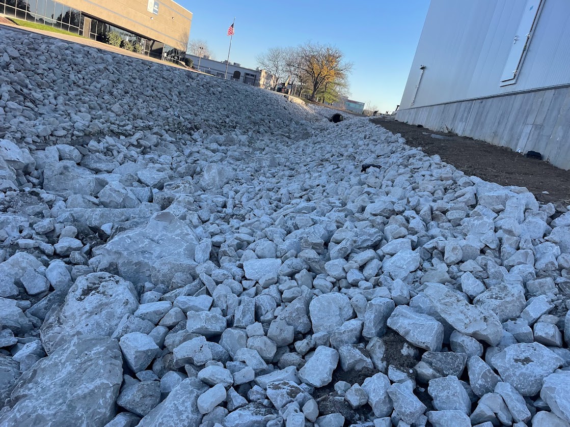 Rock-filled drainage ditch beside industrial buildings