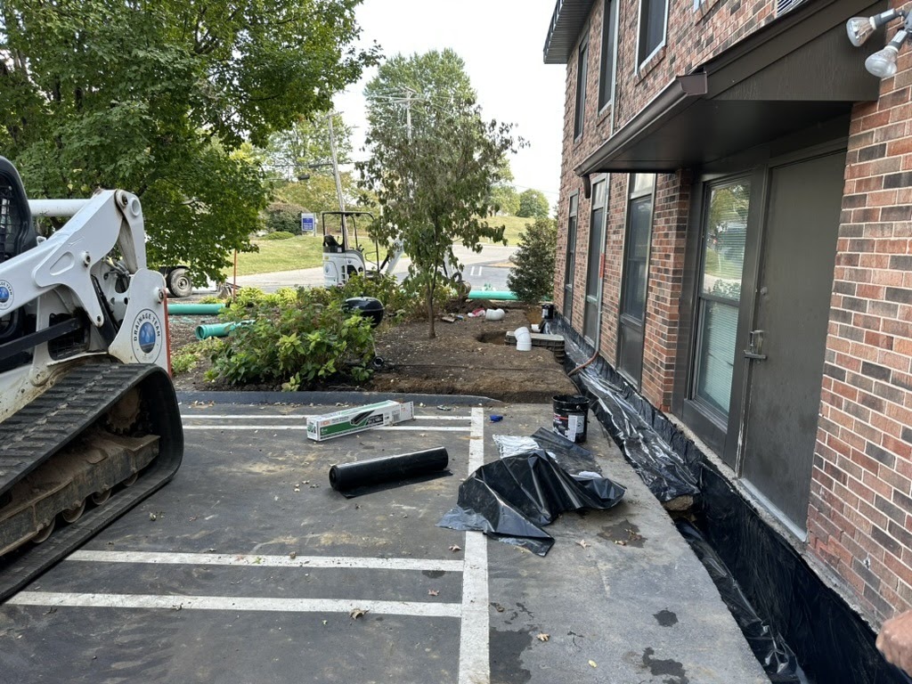 Construction work beside brick building with skid steer