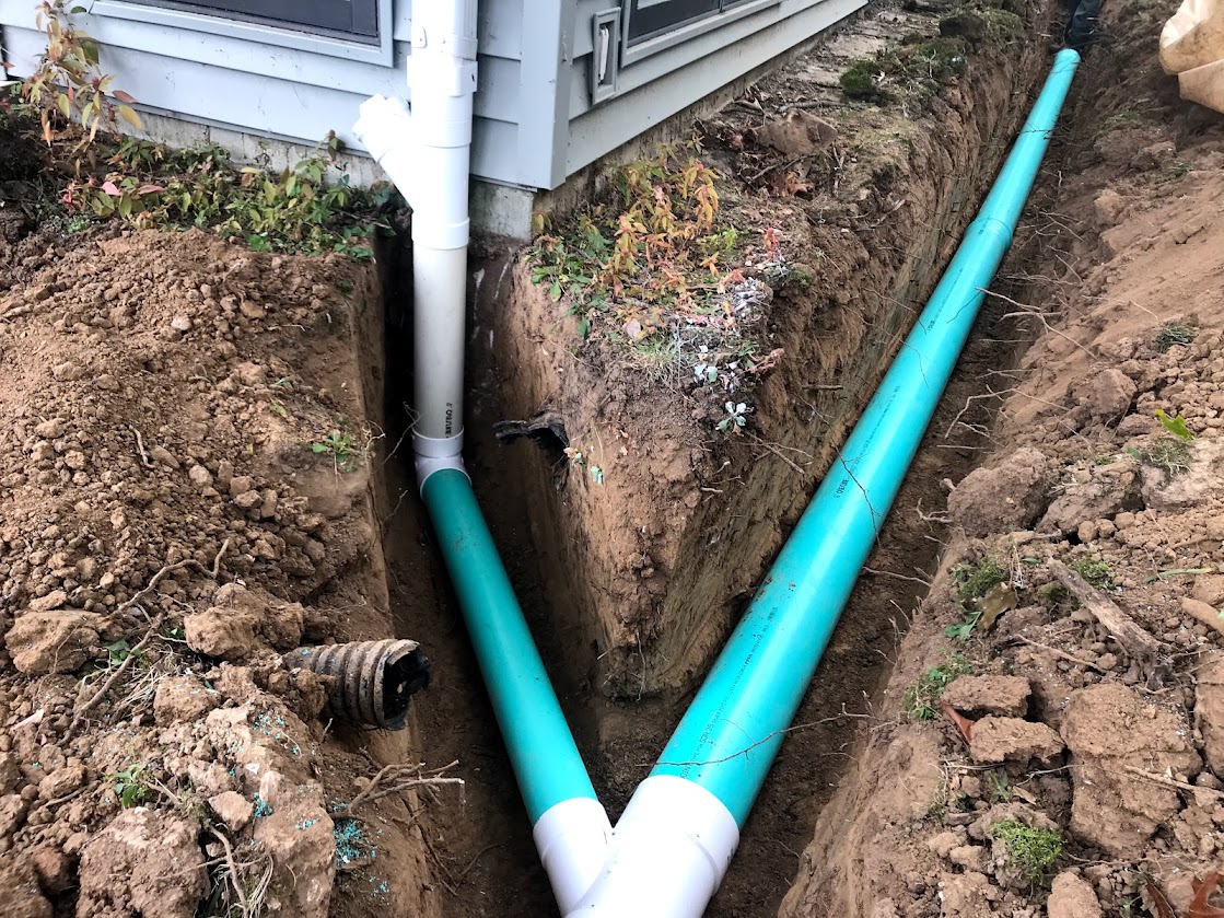 Green PVC drainage pipes in house foundation trench