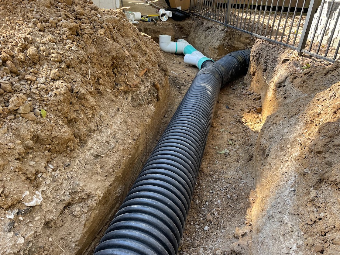 Black corrugated drainage pipe in excavated trench