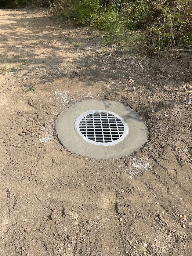 Metal drainage grate on dirt path
