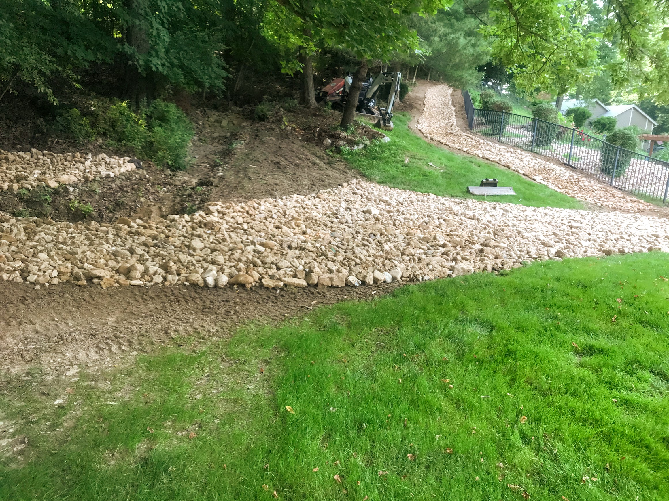 Rock drainage swale on sloped backyard hillside