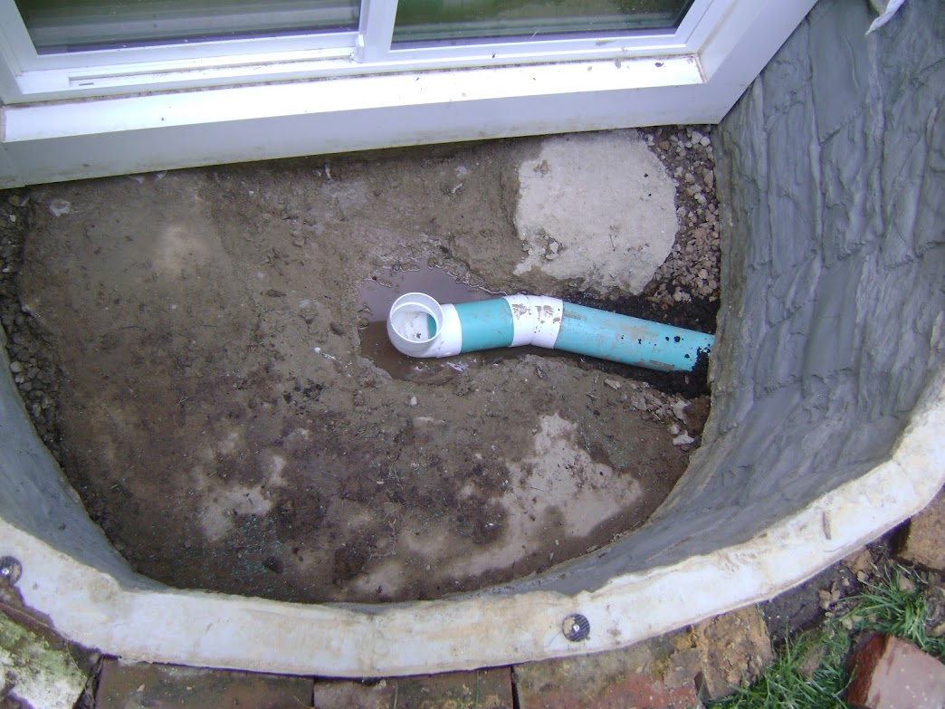 Exposed drain pipe inside window well